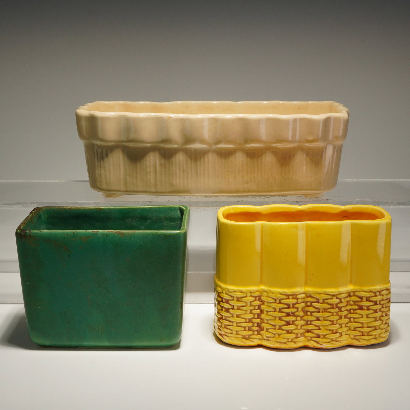 Three McCoy and Brush McCoy Pottery Ceramic Planters: Three McCoy and Brush McCoy Pottery ceramic planters in various colors and sizes. The collection includes a cream-colored rectangular planter featuring a scalloped rim, a vertically fluted body, and