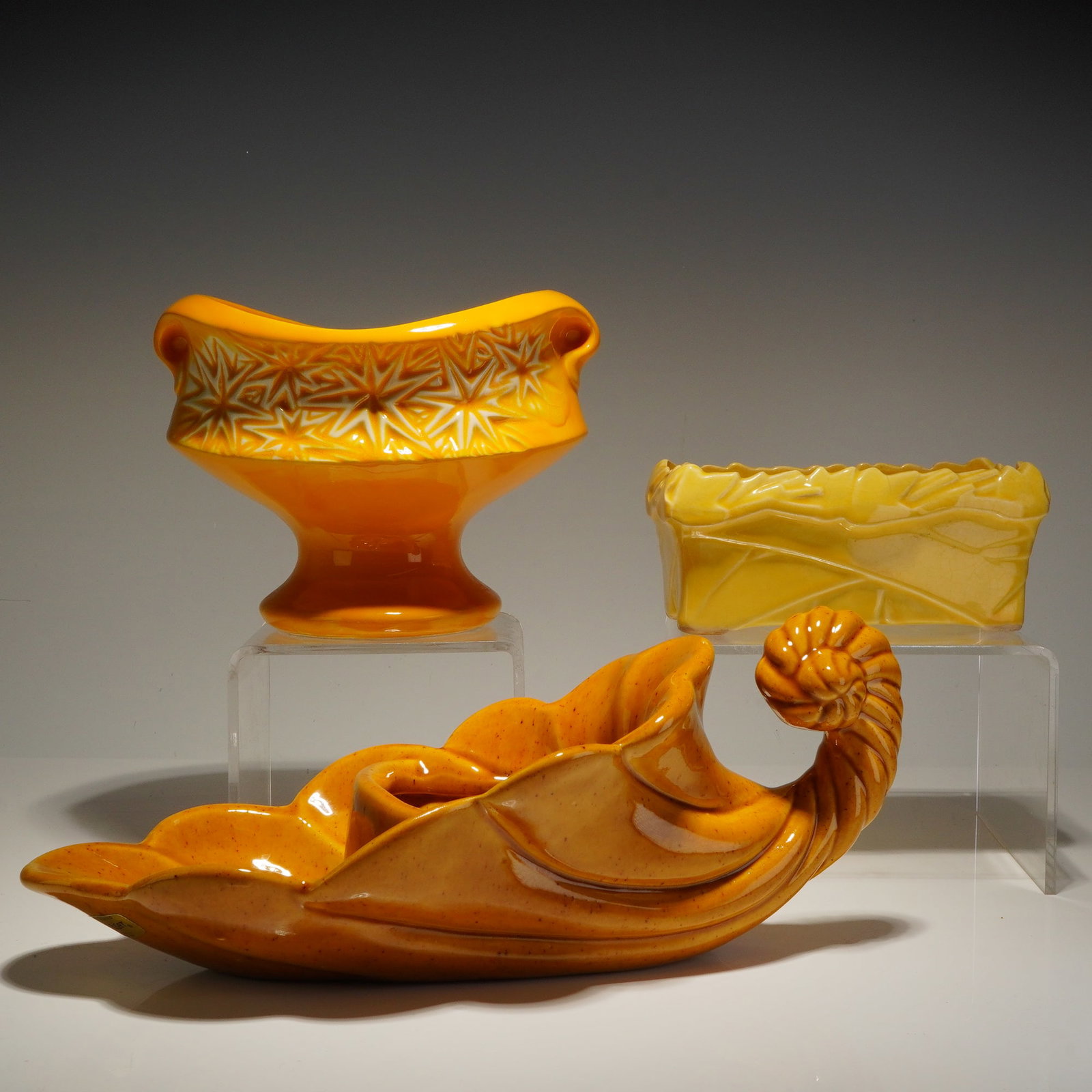 Three McCoy and Haeger Ceramic Planters in Yellow and Brown Glazes: This trio of mid-century ceramic planters features various shapes and sizes finished in yellow and brown glazes. The collection consists of two pieces by McCoy Pottery and one piece by Haeger. The