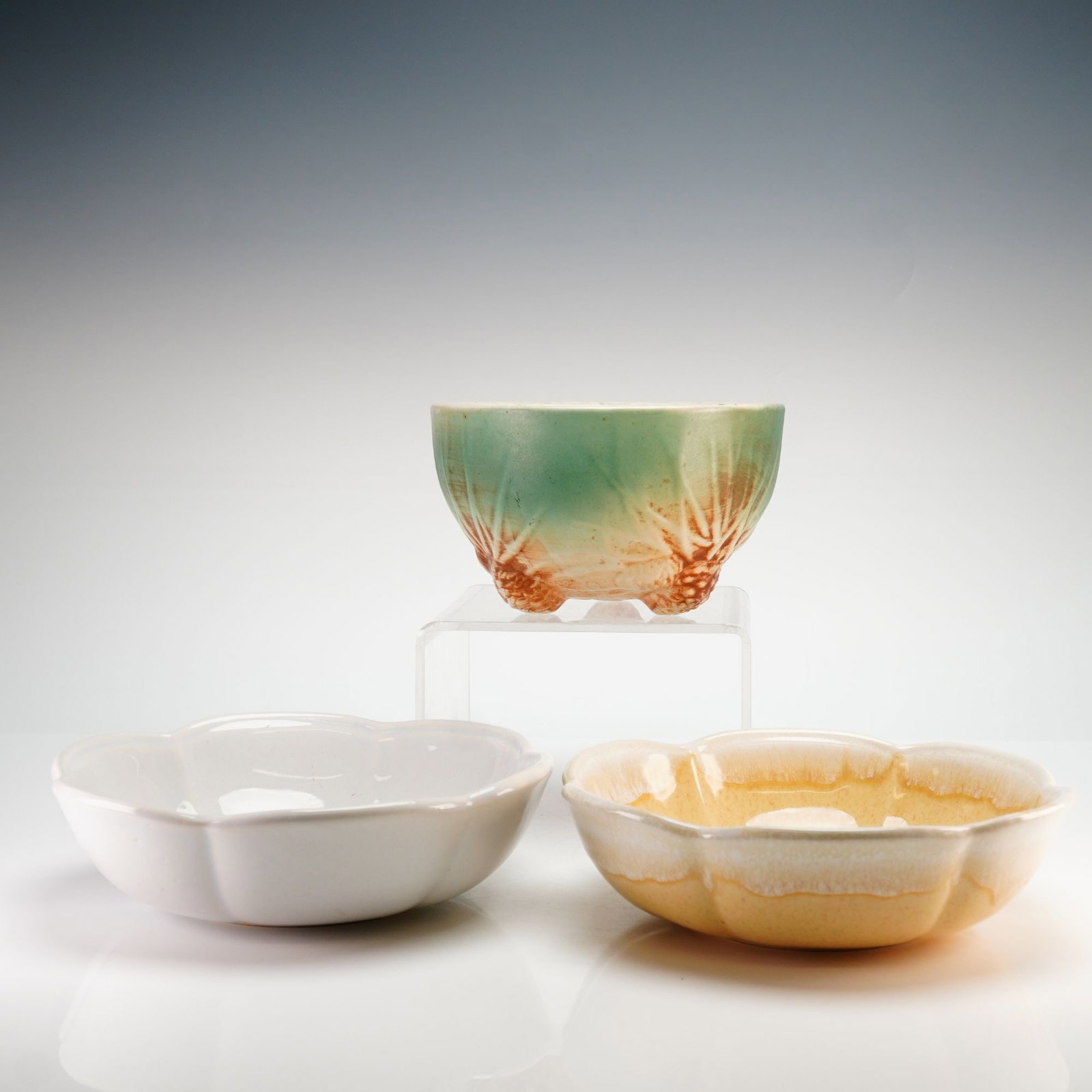 Three McCoy Pottery Bowls Including Rustic Pinecone Planter: A three-piece collection of American art pottery manufactured by McCoy. The group includes a small three-footed planter from the Rustic line featuring relief-molded pine cone and needle motifs in