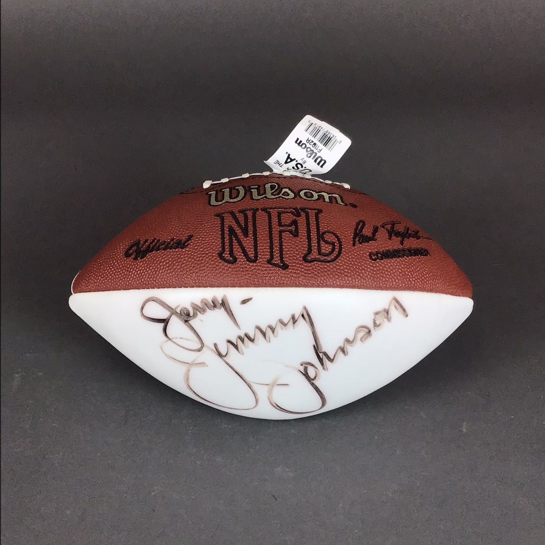 Jimmy Johnson Autographed Official Wilson NFL Football with Inscription: This is an official Wilson National Football League (NFL) football featuring a specialized two-tone design. The ball is constructed with four panels, consisting of two traditional brown pebbled leathe
