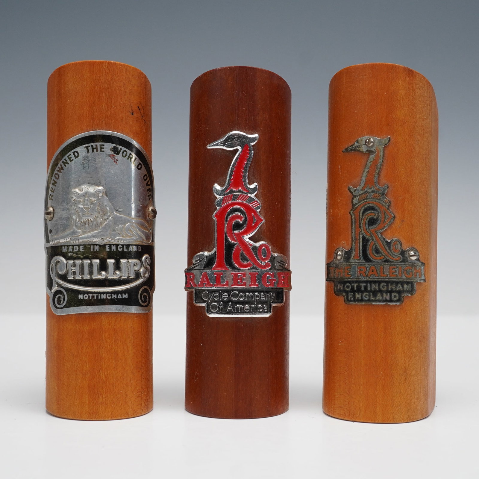 3pc Ralph W. Rogers Vintage Bicycle Head Badges: Collection includes three mounted vintage bicycle head badges displayed on custom wooden plaques. The first badge is marked "Phillips, Made in England, Nottingham" with a lion motif and the phrase "Re