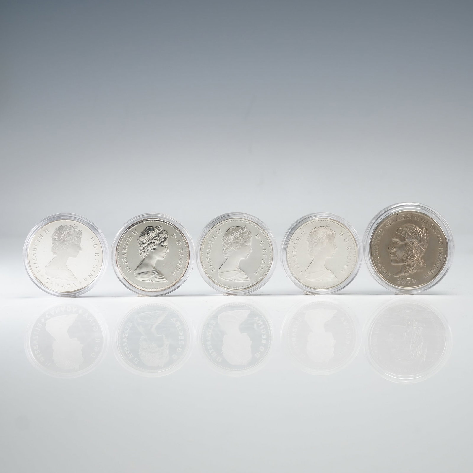 5pc 1982 Elizabeth II Canadian Dollar and 1974 U.S. Souvenir Dollar: Includes four 1982 Elizabeth II Canadian One dollar coins, issued as a 100th Anniversary of the city of founding of the city of Regina, Saskatchewan. Also included is a North Dakota Souvenir Dollar co