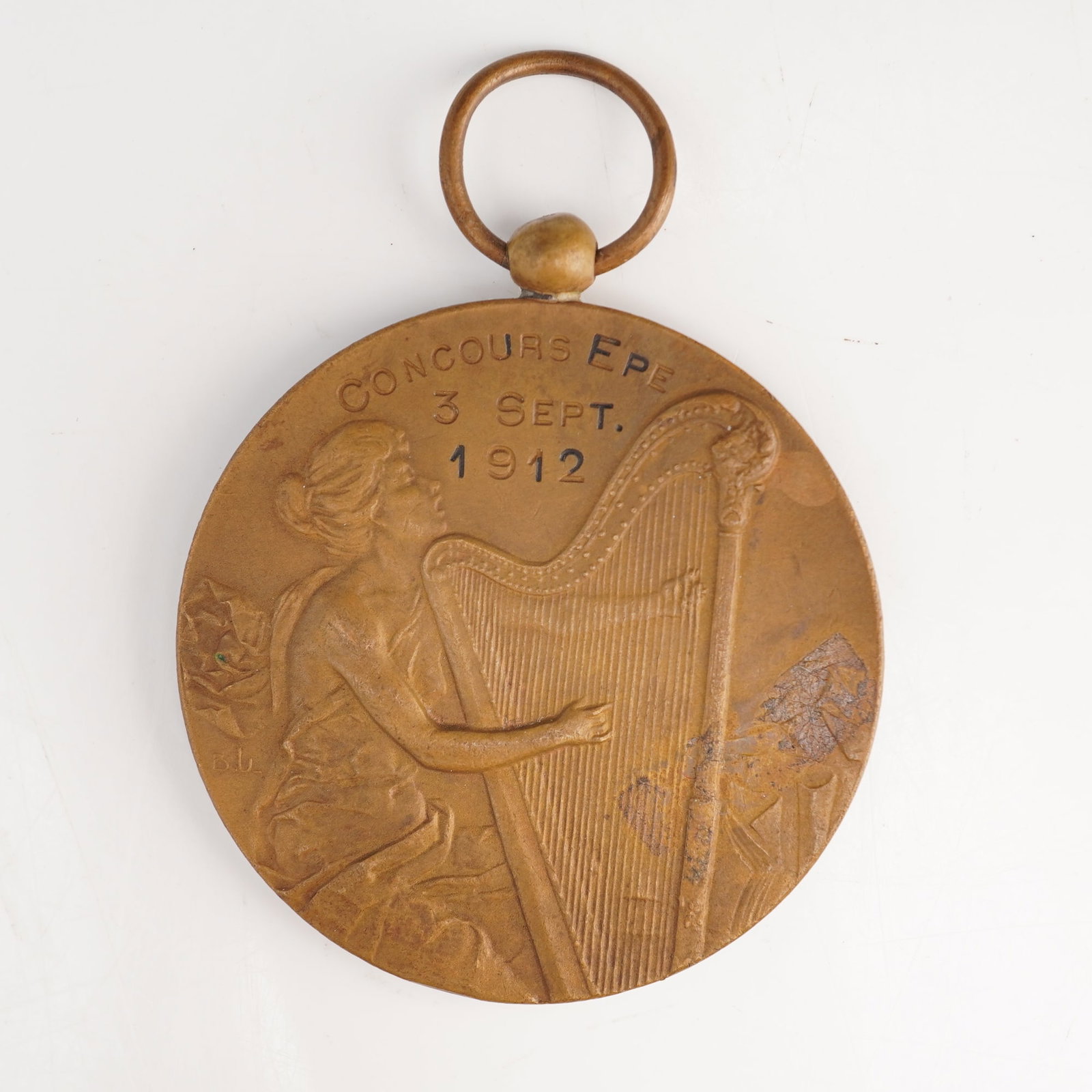 France and Netherlands, Bronze Musical Competition Award Medal, Pre-WWI (1912): This is a circular bronze award medal with suspension ring from French musical competition Concours Epe 1912. The piece reflects the Art Nouveau style prevalent in the early 20th century, likely