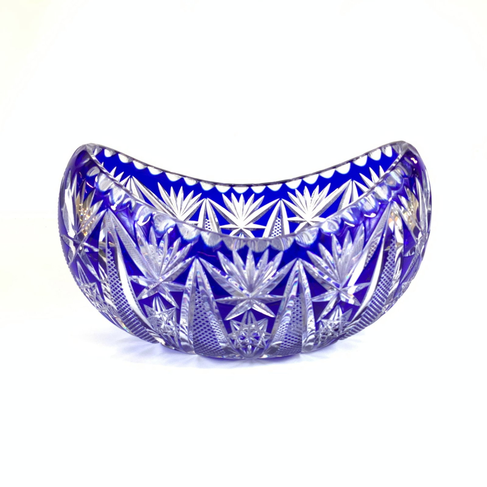 Cobalt Blue Hand Cut to Clear Crystal Boat Shaped Centerpiece Bowl: A boat shaped centerpiece bowl or basket constructed of cobalt blue cased to clear lead crystal. The vessel features a crescent profile with a scalloped rim containing circular thumbprint notches. The