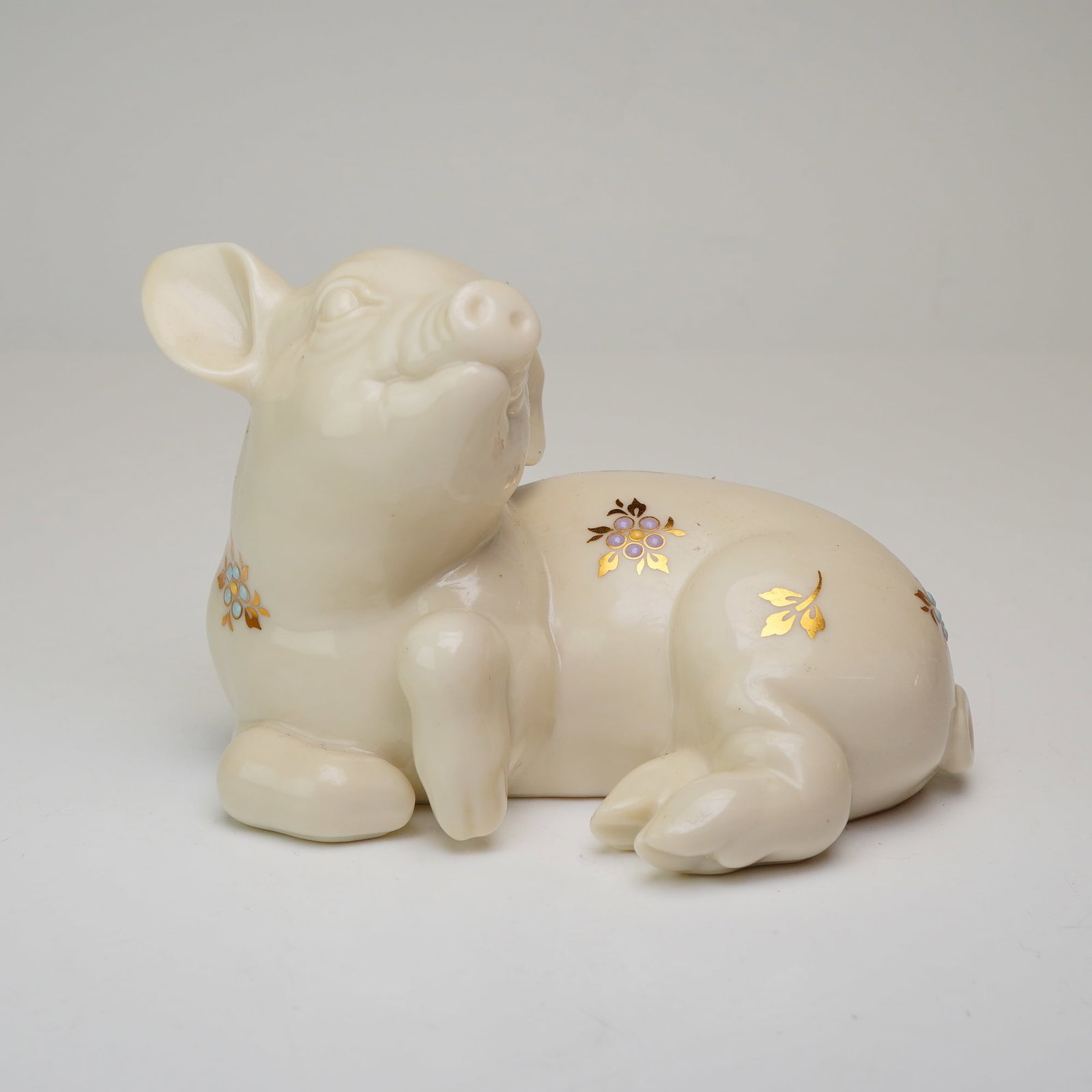 Lenox China Jewels Collection Portly Pig: This stylized reclining pig is decorated with the signature China Jewels aesthetic, featuring hand-applied raised enamel dots in shades of lavender and light blue. The piece is further accented with 2