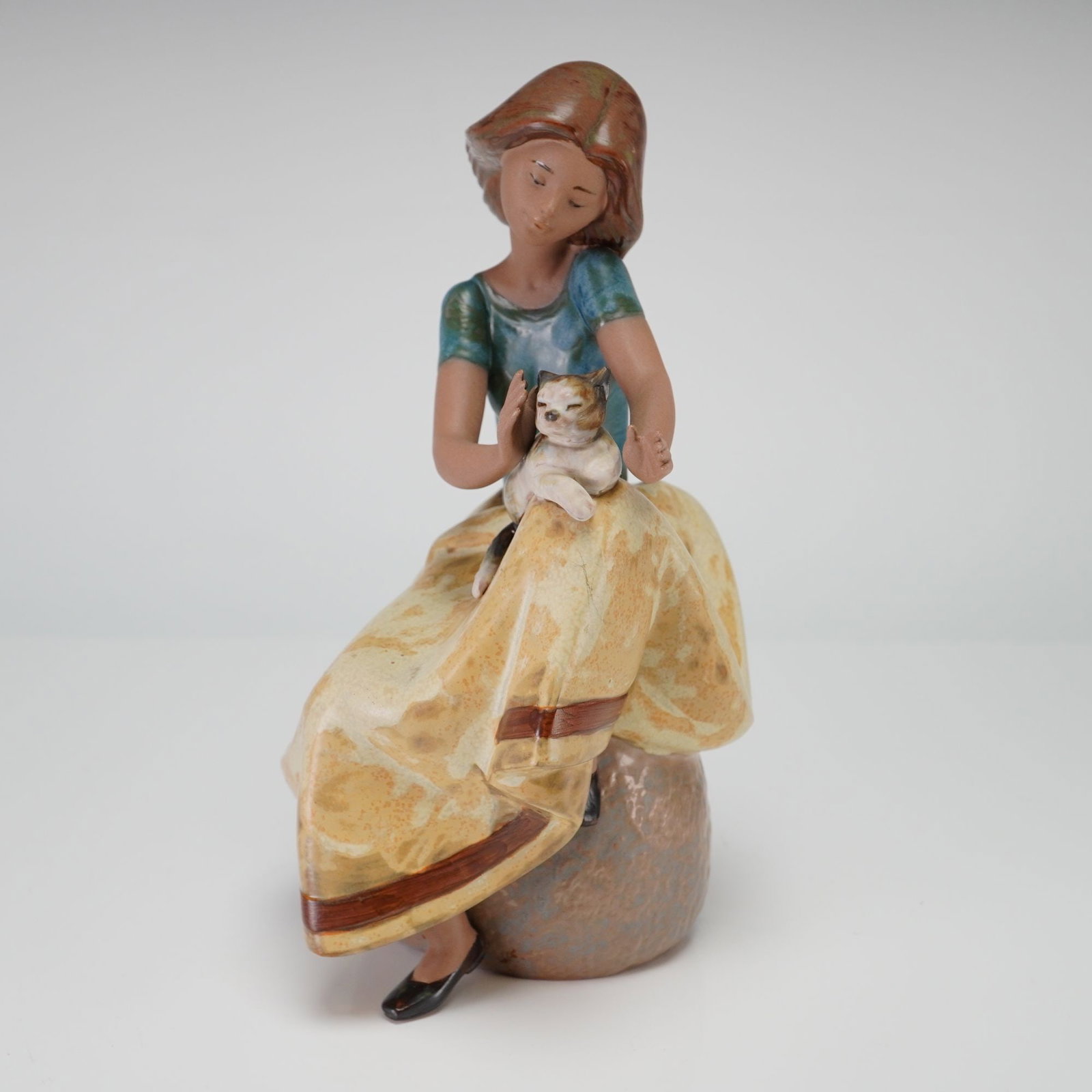 Lladro Gres Porcelain Figurine Repose Model 2169: The piece is crafted in a matte Gres finish, a textured porcelain style known for its natural, earthy tones rather than a traditional high-gloss glaze. The figurine depicts a young woman with long bro