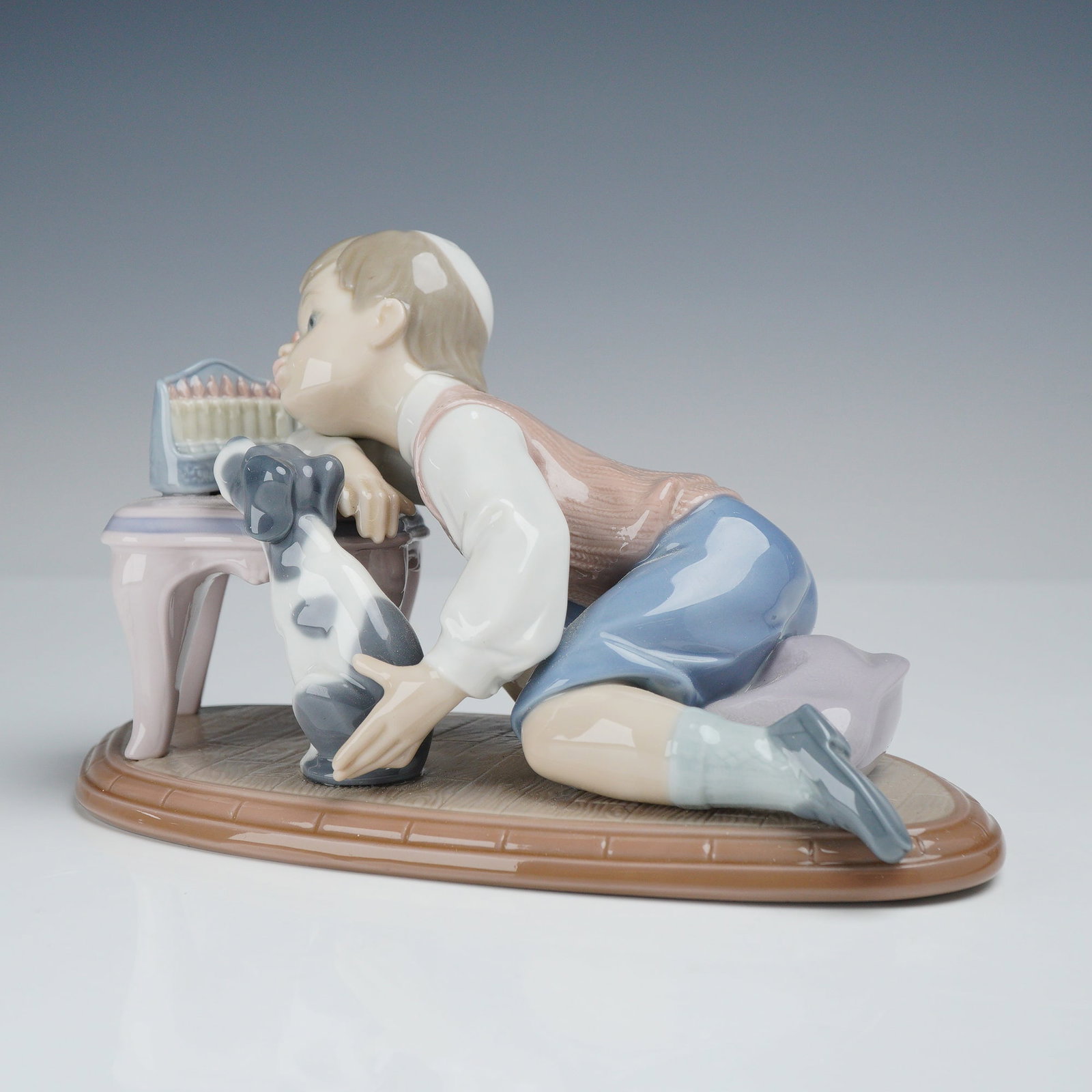 Lladro Porcelain Figurine Hanukkah Lights 01006027: This Lladro porcelain figurine, titled Hanukkah Lights and also known as Festival of Lights, was designed by sculptor Joan Coderch and issued in 1993. The polychrome glazed piece depicts a young boy w