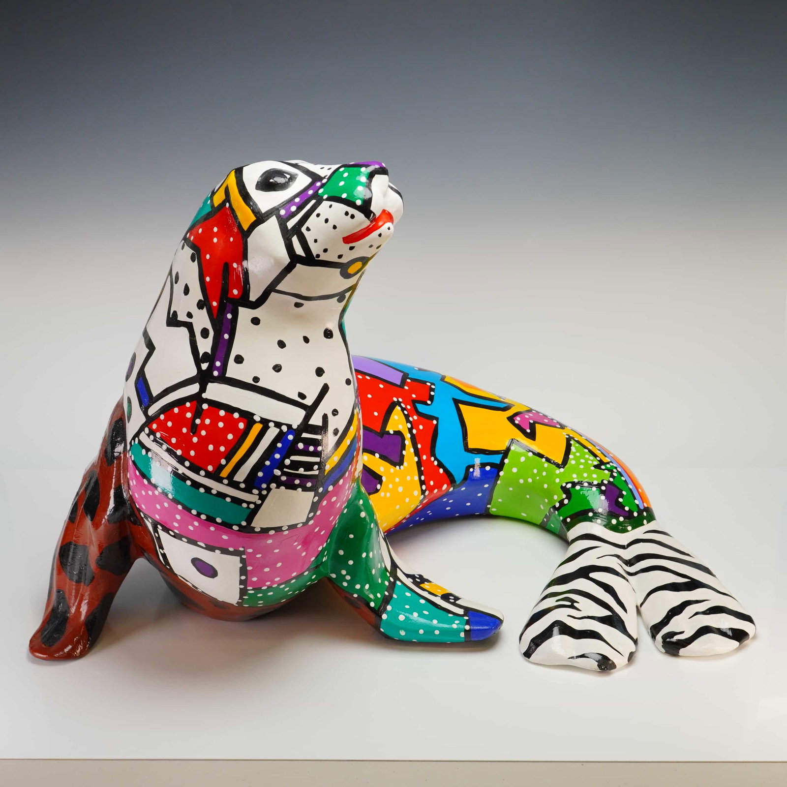 Marcie Ziv (American, 20th century) Paper Mache with Acrylic Seal Sculpture, 1994, Signed: A sculpture of a seal by artist Marcie Ziv. This contemporary pop art piece depicts a seal in a seated pose with its head turned upward. The exterior is decorated with a complex array of hand-painted