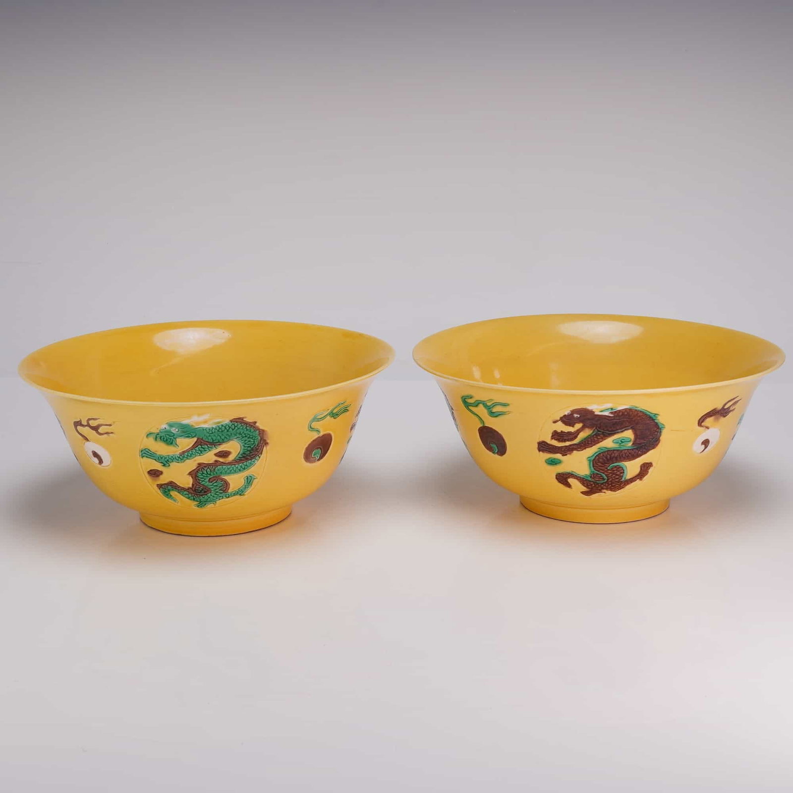 Pair of Yellow Glaze Bowls, Kangxi Mark, Dragons and Flaming Pearls: A pair of yellow glazed bowls decorated with dragons and flaming pearls in shades of brown, green, and white. Each bears Kangxi marks on the underside. DimensionsEach: 7.75"W x 3.5"H Weight2.8 lbs