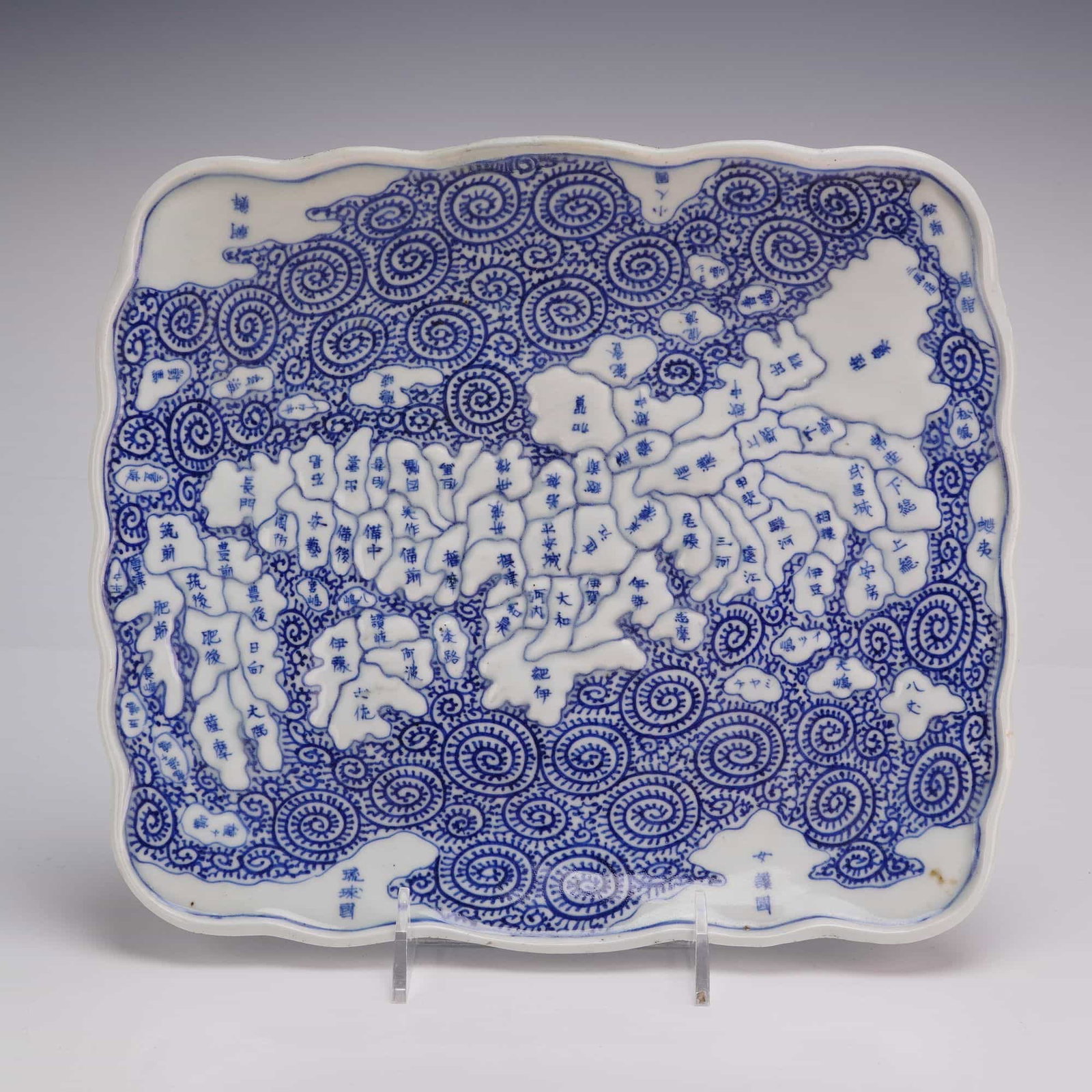 Japanese Blue and White Porcelain Rectangular Map Dish: A Japanese blue and white porcelain rectangular dish with a scalloped rim, featuring a relief map design and swirl pattern. The underside bears blue Japanese characters. Dimensions111.5"L x 10"W x 1.5