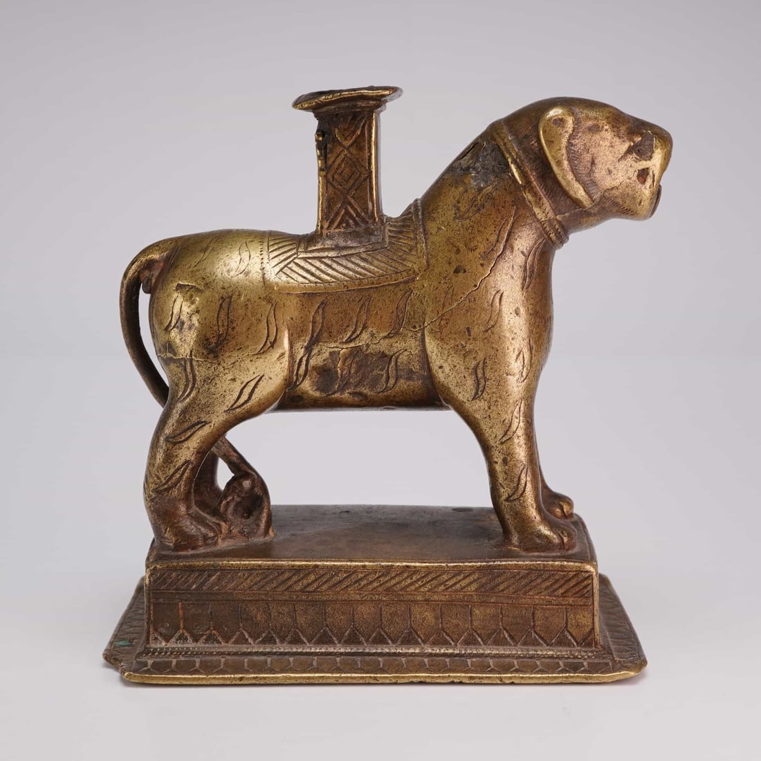 Indian Bronze Tiger Form Incense Burner: A gold-tone bronze incense burner in the form of a tiger, mounted on a rectangular base and featuring incised patterns. Dimensions4.5"L x 2.5"W x 5"H Weight1.15 lb