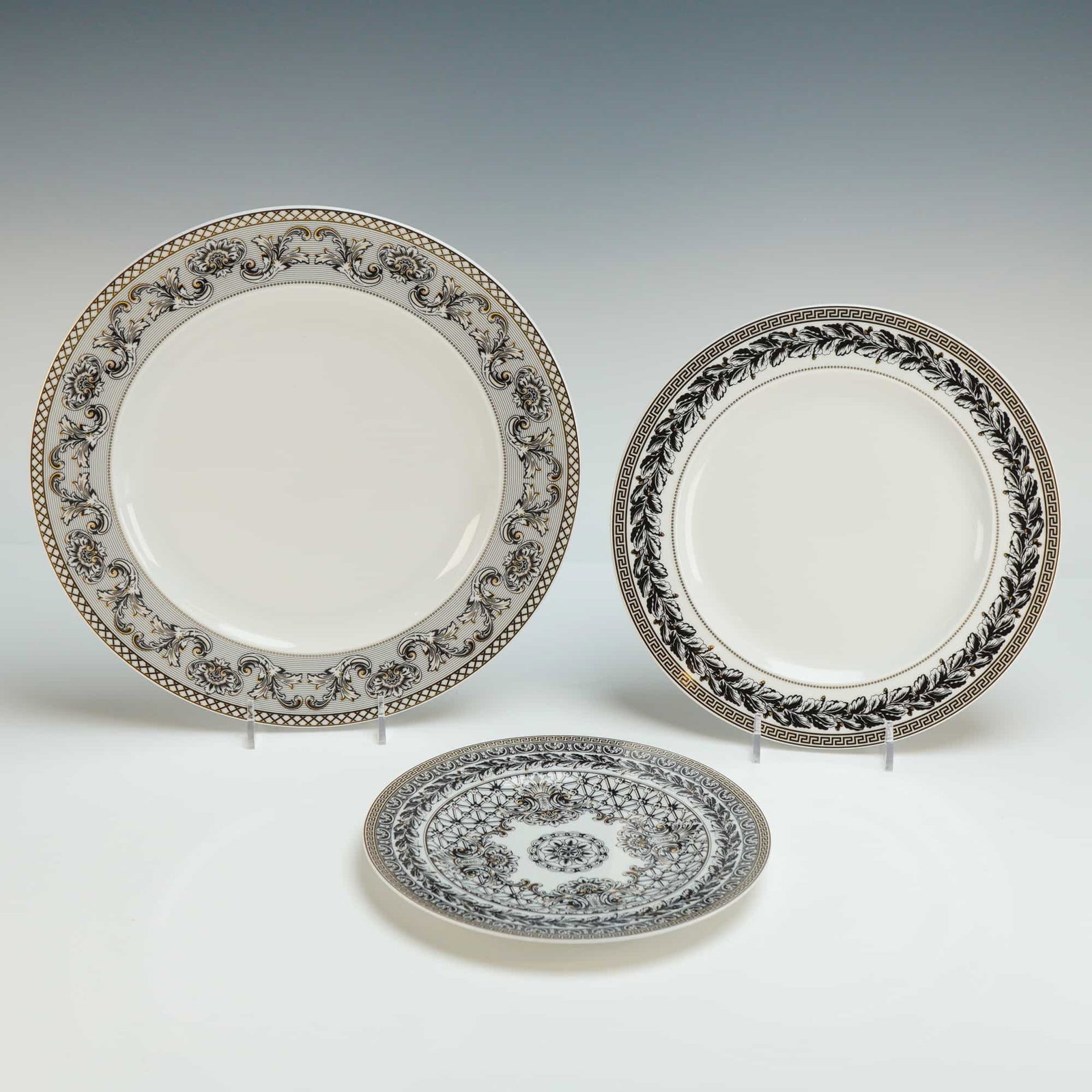 3pc Versace Rosenthal Porcelain Plate Set, Marqueterie: Each piece features elaborate neoclassical designs with intricate black and gold-toned motifs on a white ground. The decoration includes meander or Greek key borders, laurel wreaths, acanthus