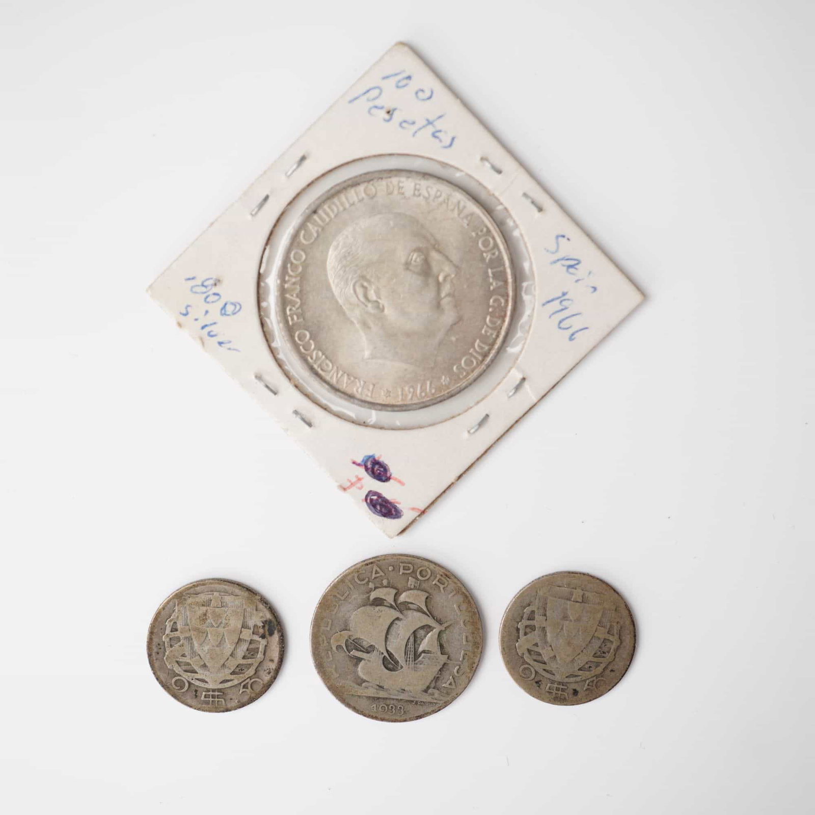 4pc Spain and Portugal Silver Coins: A four-coin group including one Spanish 100 Pesetas coin dated 1966 and three Portuguese coins consisting of two 2.50 Escudos pieces dated 1943 and one 5 Escudos piece dated 1933. The Spanish coin fea