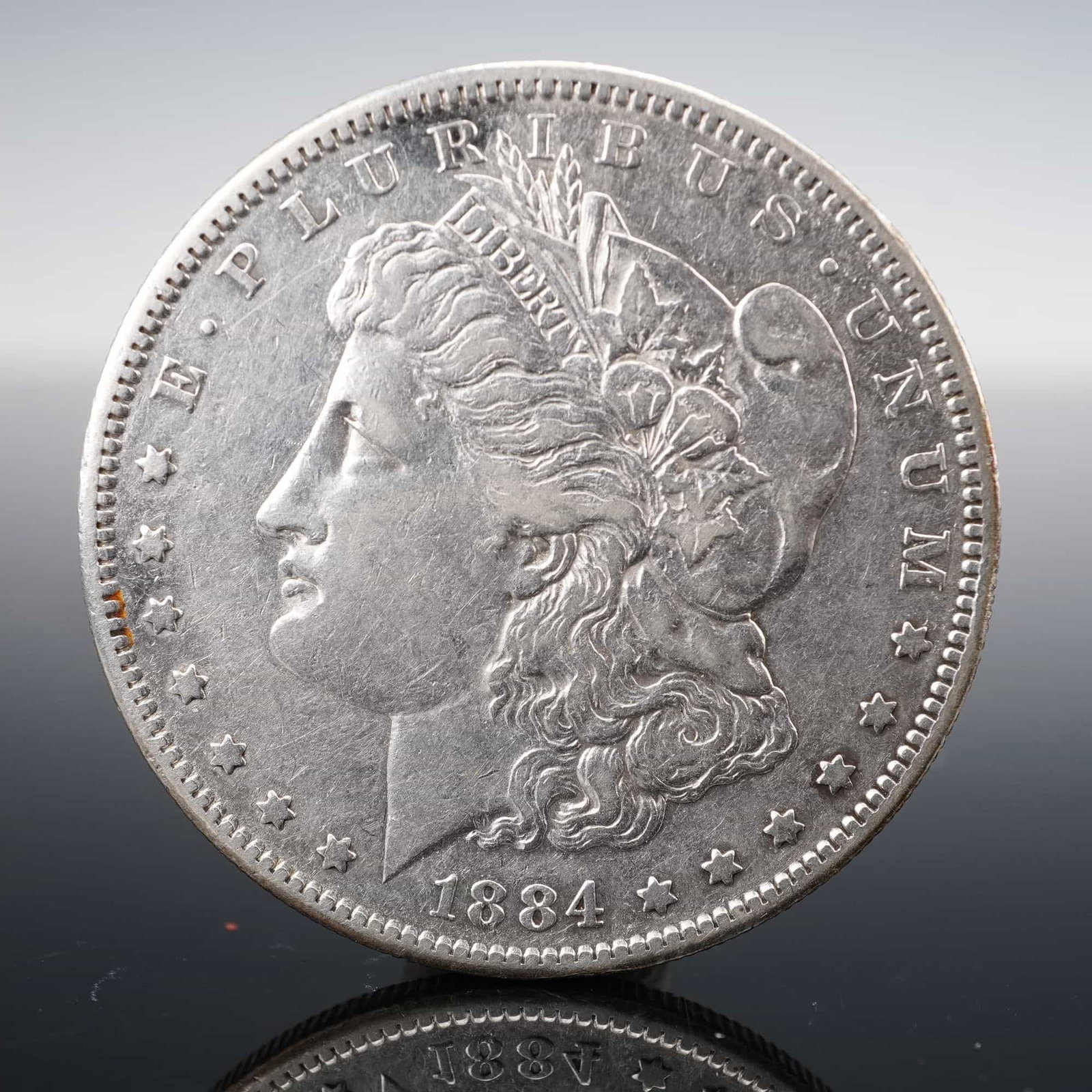1884-S Morgan Silver Dollar: Issued in 1884 at the San Francisco Mint, this Morgan Silver Dollar was struck in the standard alloy of 90% silver. The obverse presents George T. Morgan's neoclassical portrait of Liberty, adorned wi
