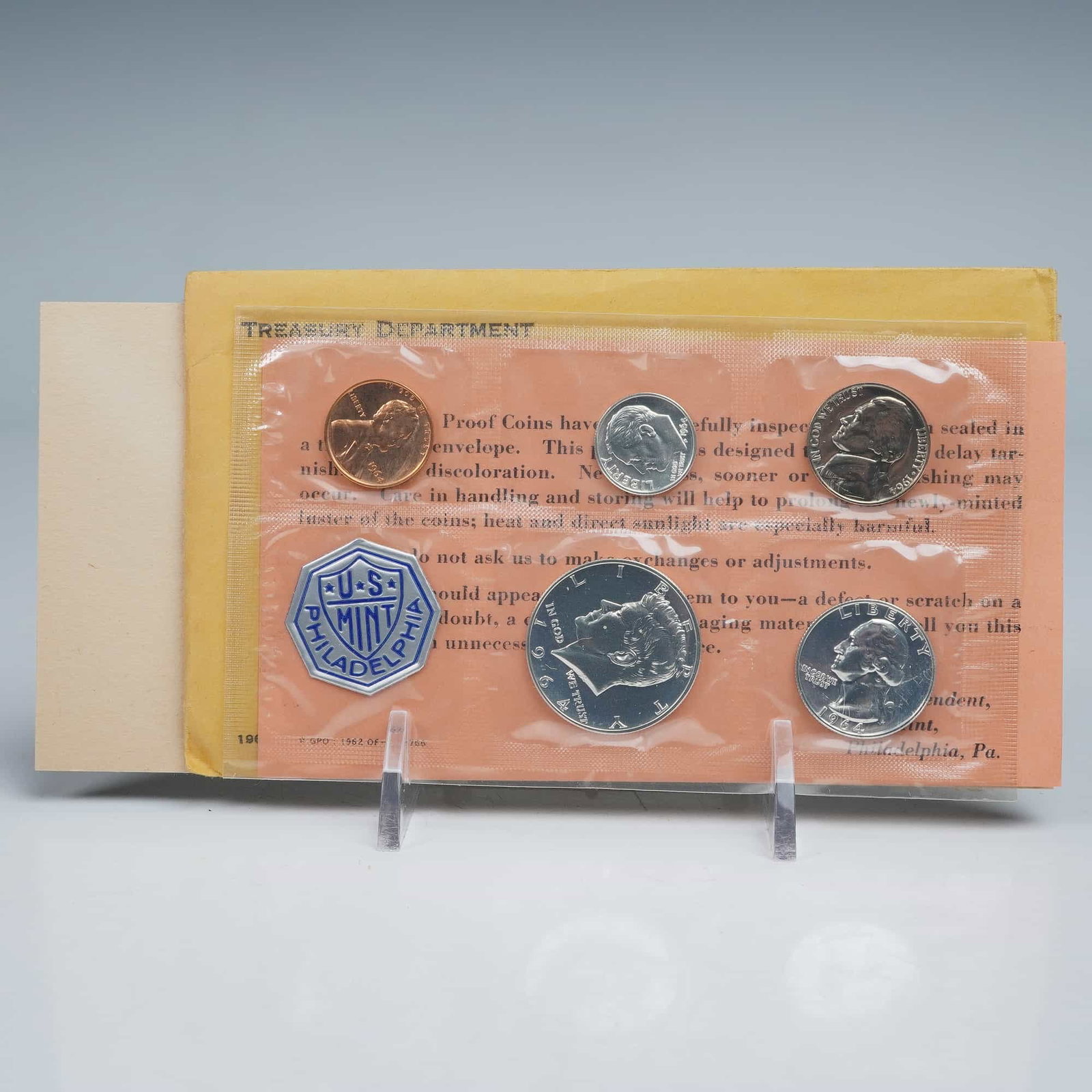 1964-P Proof Set of 5 Coins & Mint Token: This official U.S. Mint issue includes a Lincoln Cent, Jefferson Nickel, Roosevelt Dime, Washington Quarter, and Kennedy Half Dollar, each displaying mirror-like proof surfaces. The obverse designs fe