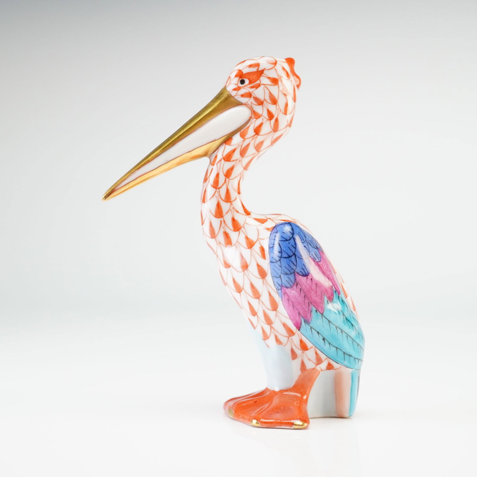 Herend Porcelain Miniature Figurine, Pelican: A Herend hand-painted porcelain figurine of a small pelican. The piece is decorated in the traditional Herend fishnet pattern in rust across the body, neck, and head. The wings are accented with multi