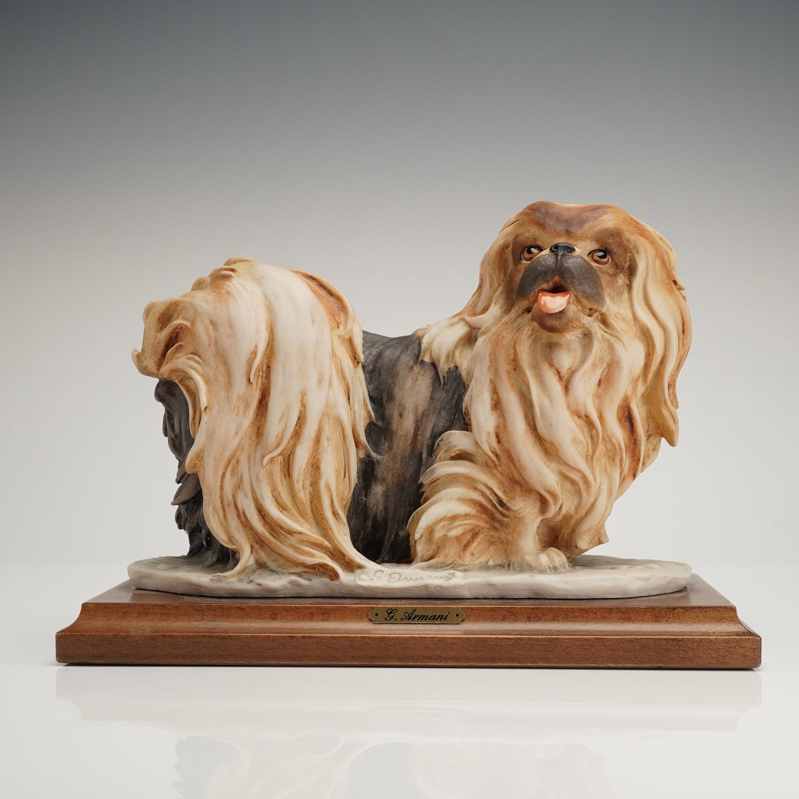 Giuseppe Armani Dog Figurine, Pekingese: The figurine is rendered in a naturalistic style with highly detailed, flowing fur painted in shades of tan, brown, and cream over a darker body color. The Pekingese is attached to a rectangular, stai