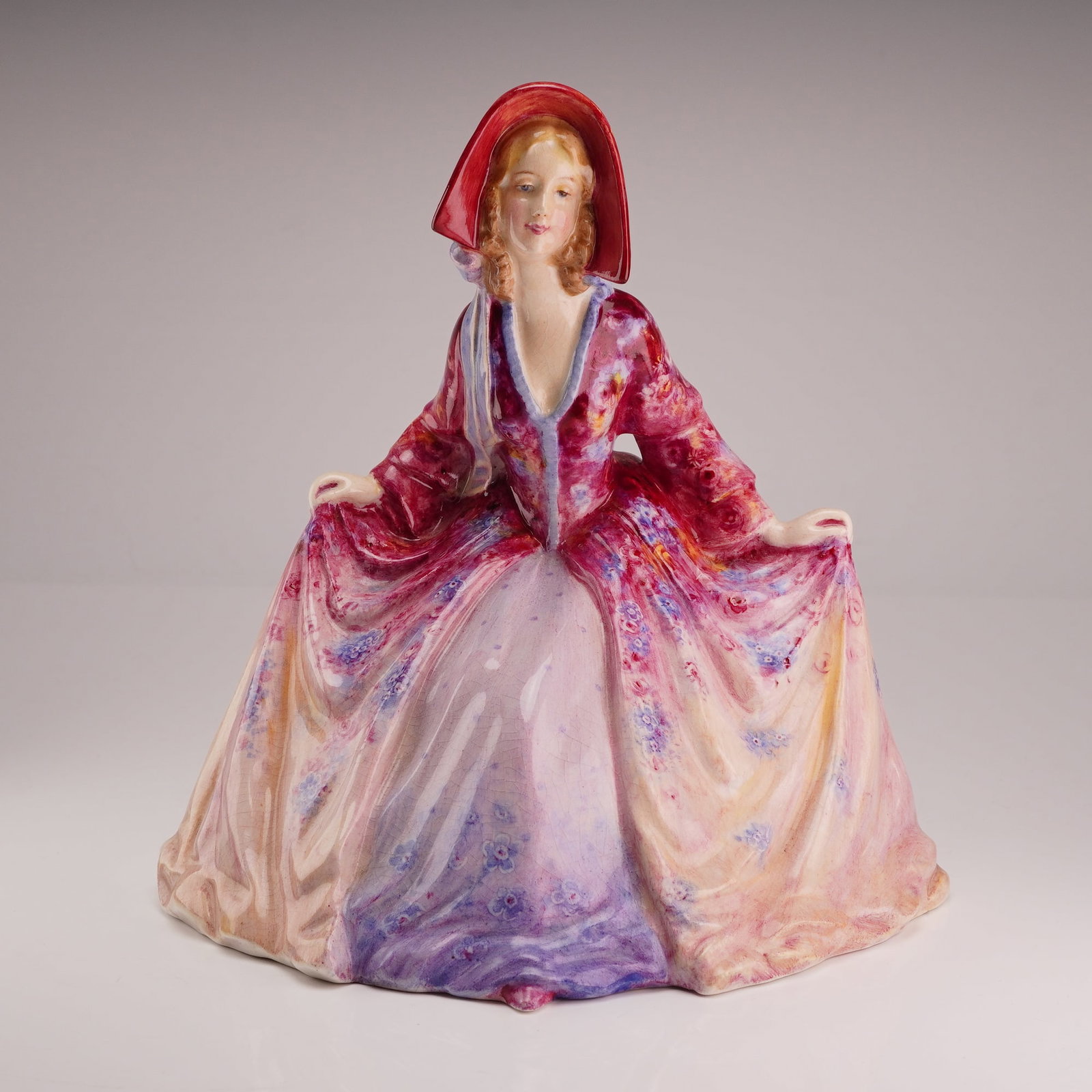 Leslie Johnson Lady Curtseying Figurine: Leslie Johnson's tenure at Royal Doulton spanned one of the most creative eras in the pottery industry. Active mainly from 1900 to 1920, he focused on hand-painted porcelain plaques and decorative fig