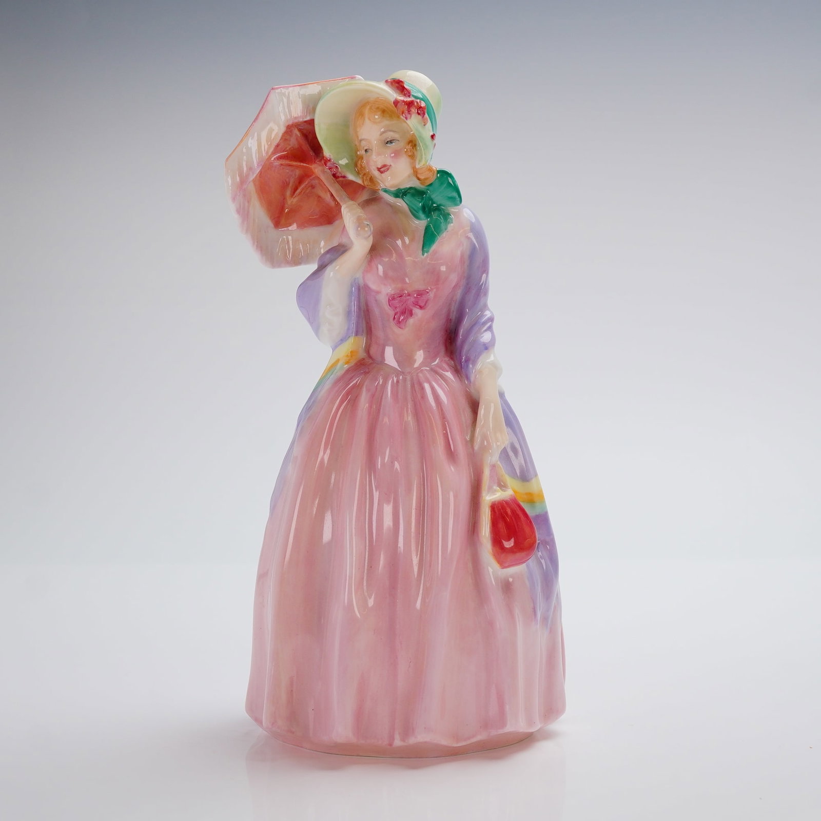 Royal Doulton Figurine, Miss Demure HN1402: A Royal Doulton Figurine, model number HN 1402, titled "Miss Demure." The piece is crafted from glazed bone china and features polychrome hand-painted decoration. The figurine depicts a standing woman