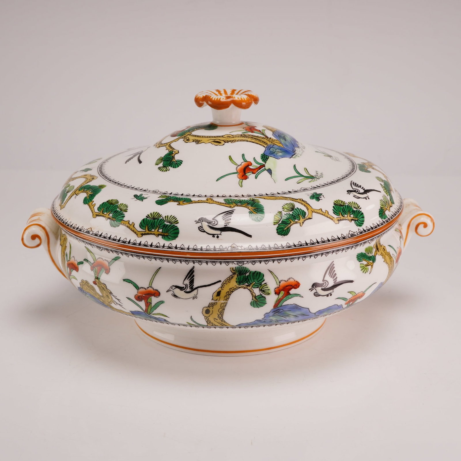 Wedgwood Chinoiserie Earthenware Covered Tureen: This Wedgwood covered serving dish or tureen is crafted from fine earthenware. The piece features a circular, shallow, footed body with two scrolling handles accented with gilding. It is accompanied b