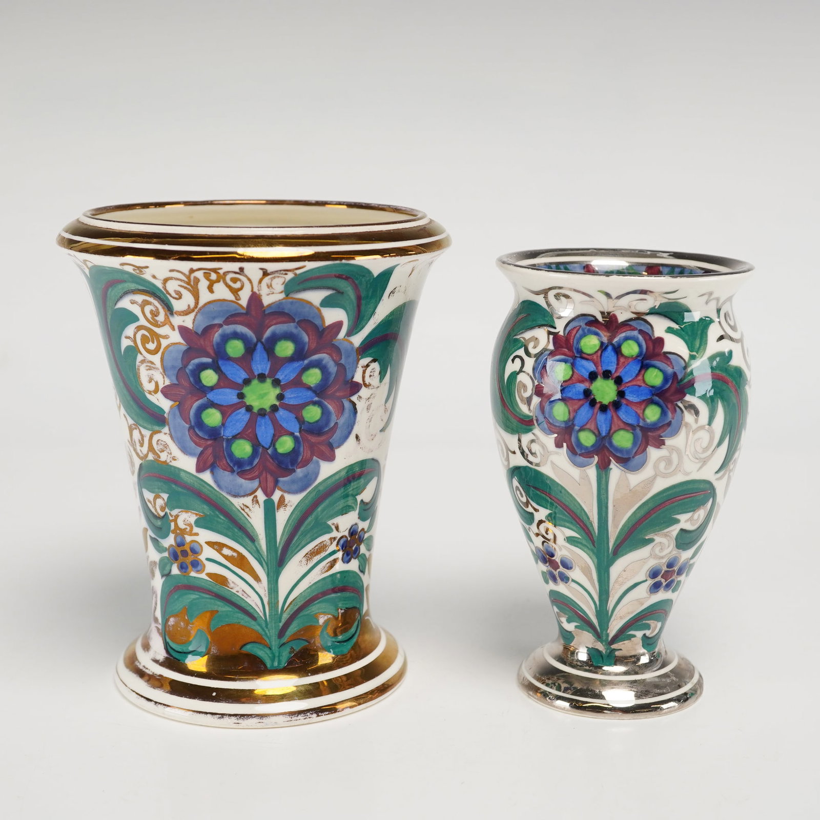 2pc Wedgwood Hand Painted Porcelain Floral Vases: This pair of Wedgwood fine porcelain vases features hand-painted Iznik-style floral motifs in blue and purple with scrolling acanthus foliage. The larger trumpet-form vase is accented with gold gildin