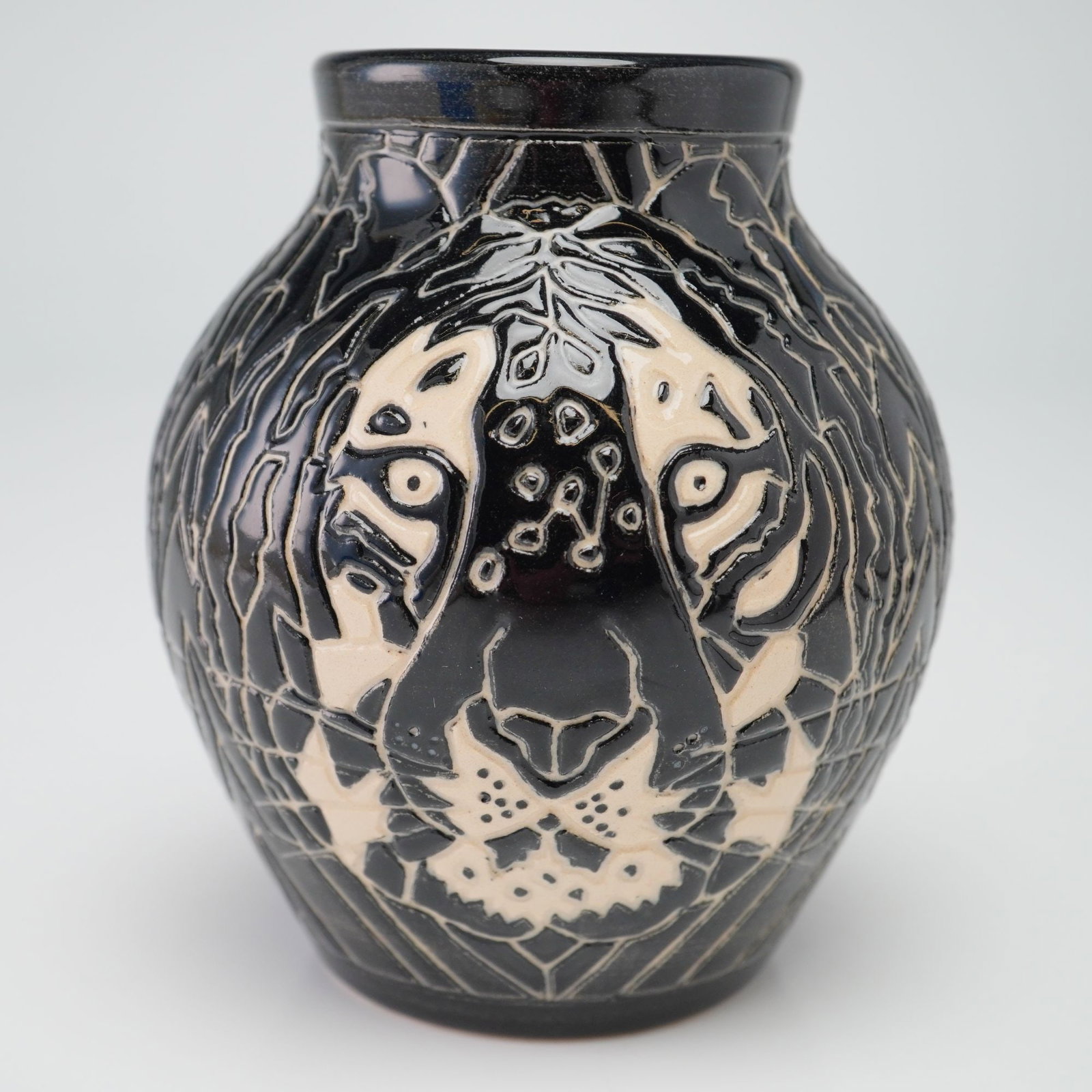Dennis China Works Pottery by Sally Tuffin Miniature Vase, Tiger on Black: The vase has a bulbous form with a short, flared neck and a solid, black-glazed interior. The exterior features a stylized tiger face and dense geometric patterns, hand-carved through the black slip t