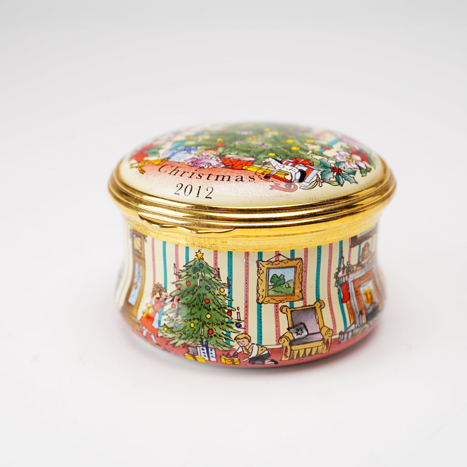 Halcyon Days English Enamel Treasure Box, Christmas 2012: A Halcyon Days enamel on copper treasure box featuring the Christmas 2012 theme. The round box consists of a domed lid and a cylindrical base joined by a gilded metal hinge and mount. The lid depicts