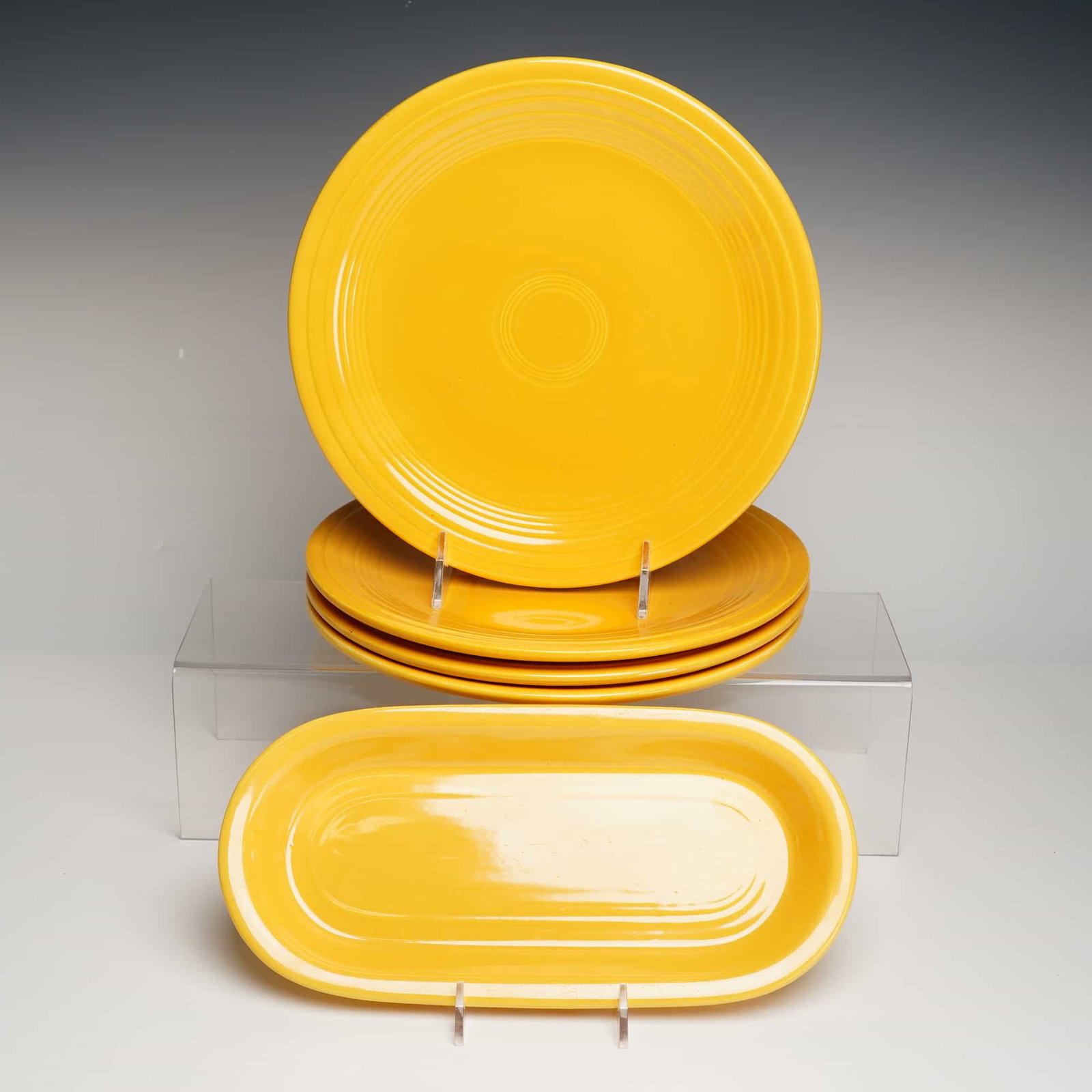 Fiesta Sunflower Yellow Plates and Platter Set: A five-piece collection of yellow glazed ceramic dinnerware from the iconic Fiesta line, manufactured by the Homer Laughlin China Company. The set comprises four round dinner plates and one elongated 