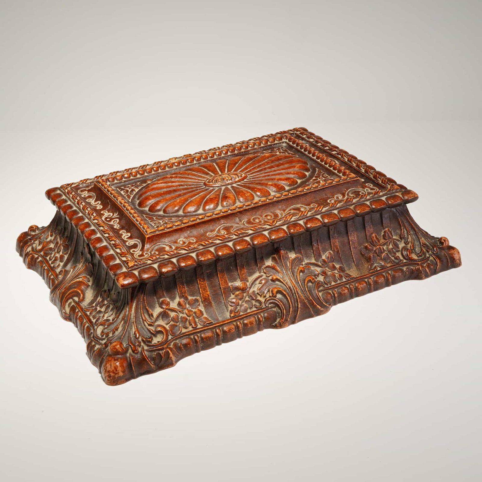 Vintage Syroco Wood Ornate Hinged Lidded Box: This vintage Syroco wood hinged lidded box is manufactured from a molded wood pulp and resin composite. The rectangular lid is detailed with a central gadrooned sunburst motif, scrollwork, and a gadro