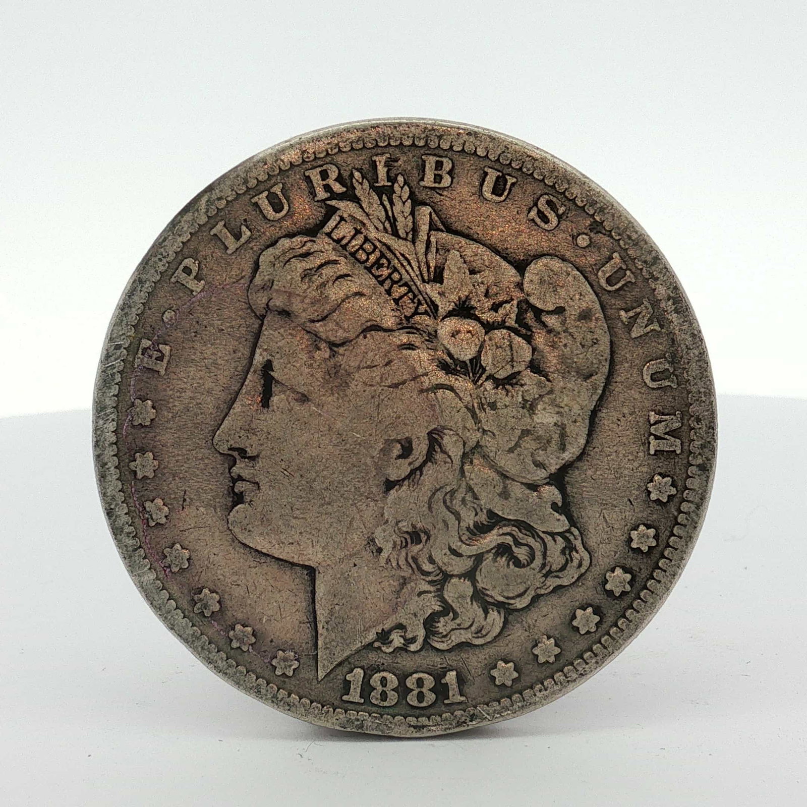 1881-S US One Dollar Morgan Silver Dollar, Circulated: This US Morgan dollar is dated 1881 and was struck at the San Francisco Mint. The coin is composed of 90% silver and 10% copper. The obverse features the legend E PLURIBUS UNUM and the date 1881, whil