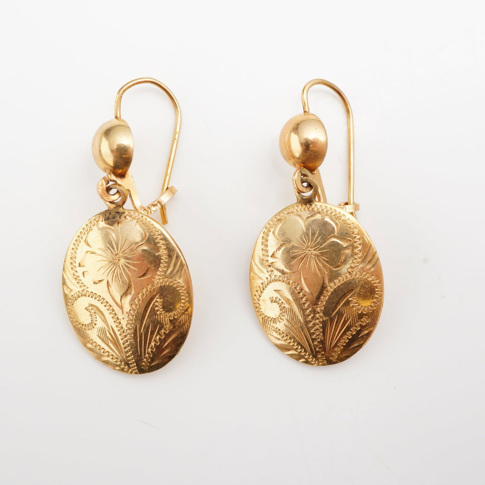 Pair of 14K Gold Floral Relief Drop Earrings: A pair of 14K gold pendant earrings featuring a detailed floral relief design. Each earring is crafted with a circular drop showcasing a textured botanical motif, suspended from a classic polished hoo