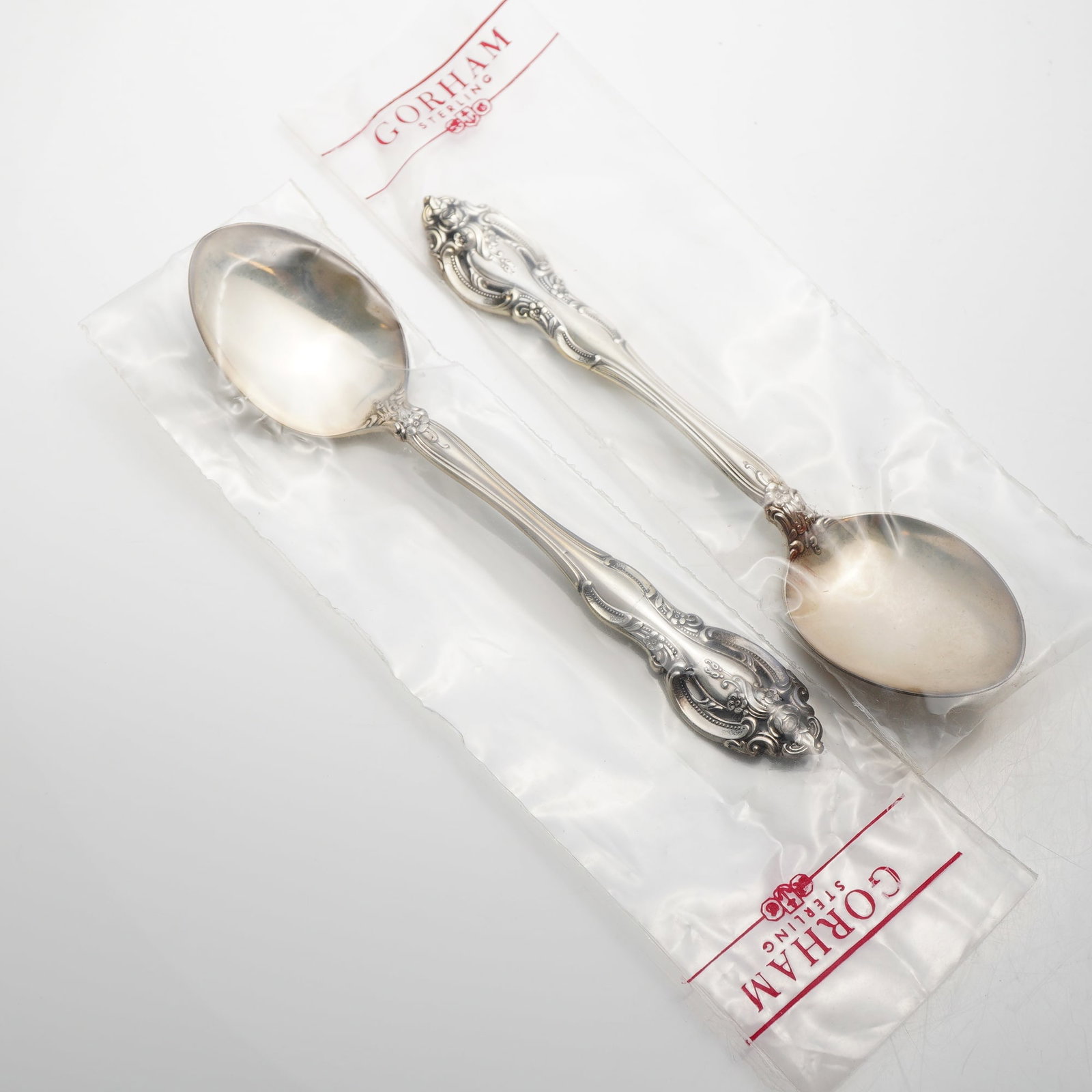 2pc Gorham Sterling Silver Spoons, La Scala: A pair of spoons manufactured by the Gorham Manufacturing Company in the La Scala pattern. The design features a deeply carved, pierced handle decorated with elaborate scrollwork and a rose at the top