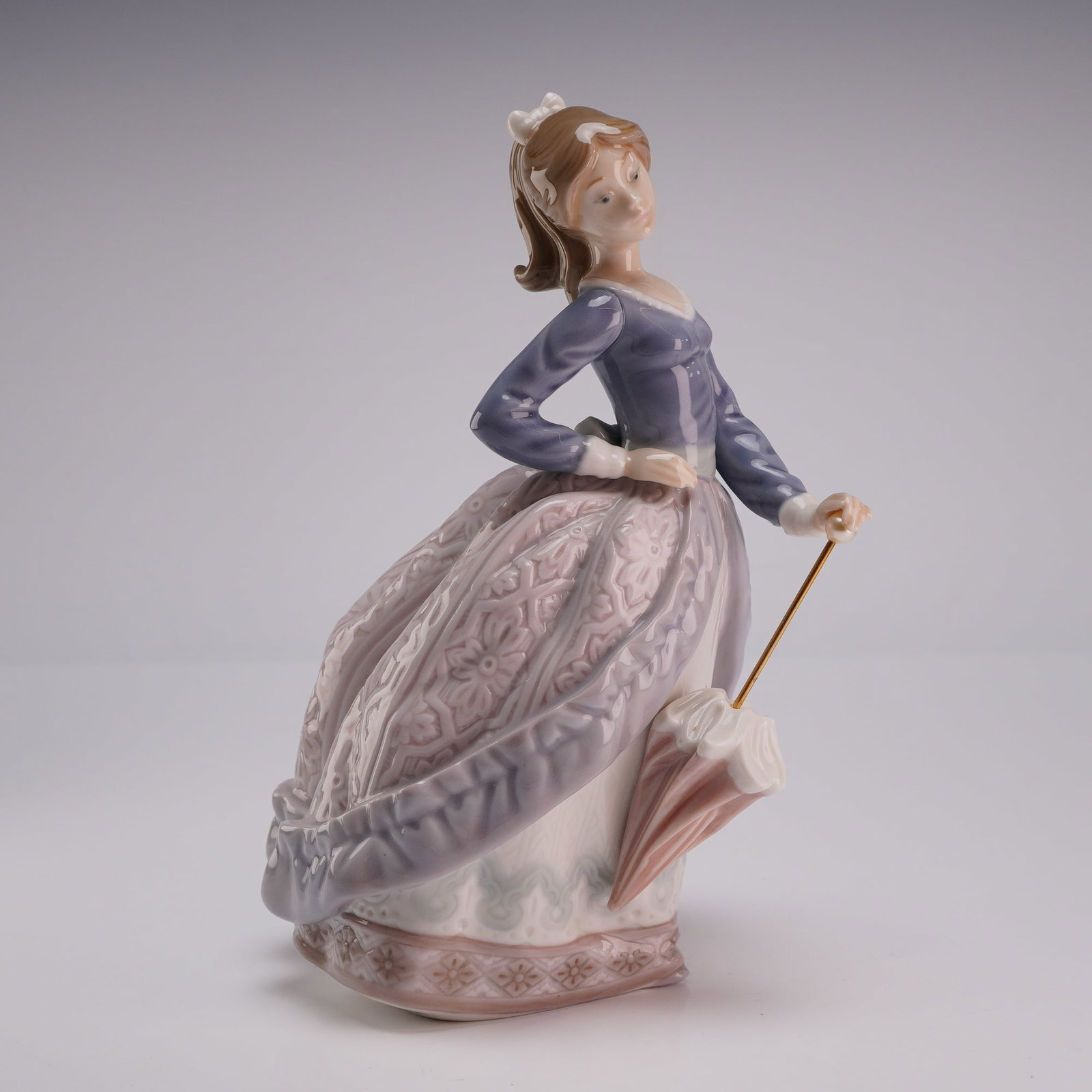 Lladro Porcelain Figurine Evita 01005212: Lladro glazed porcelain figurine titled Evita designed by Jose Puche. The figurine depicts a young woman in a full-skirted dress with her hair styled in a ponytail tied with a white bow. She is shown 