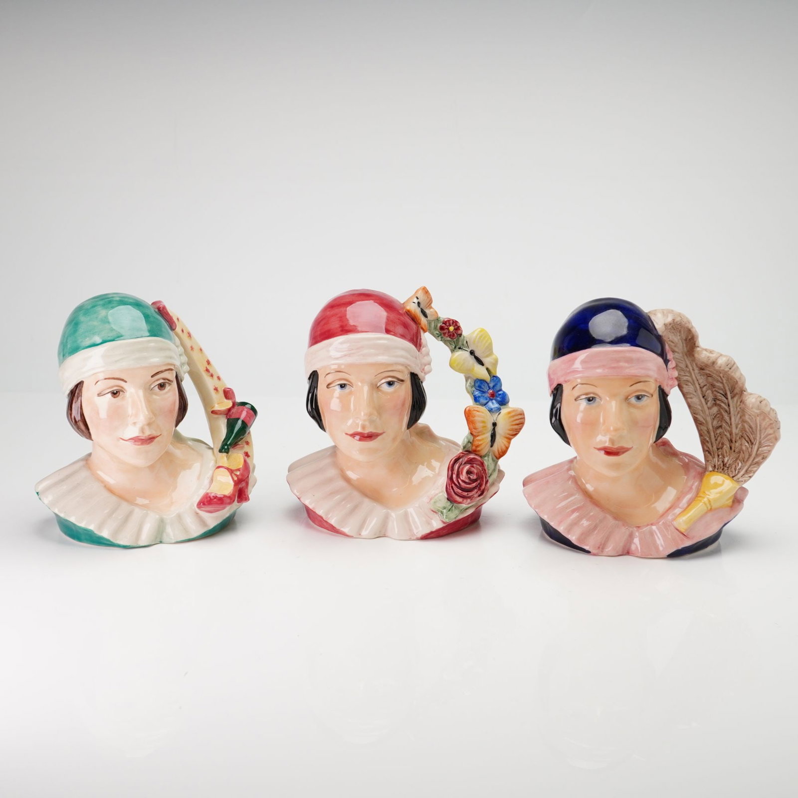 3pc Kevin Francis Limited Edition Art Deco Girl Jugs by Andy Moss: Each piece was modeled by artist Andy Moss and features a stylized female bust in the Art Deco tradition, wearing a wide ruffled collar and a close-fitting hat. The figures are hand-made and hand-pain