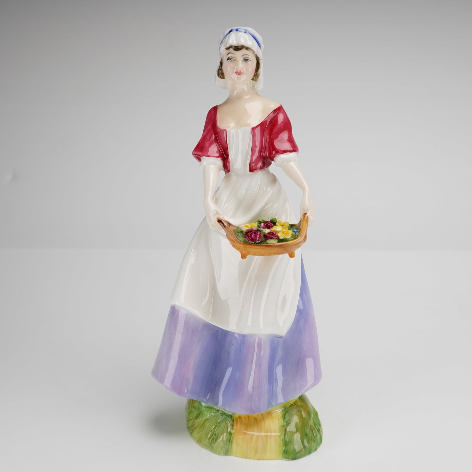 Royal Doulton Dawn HN 3258 Bone China Figurine: A Royal Doulton bone china figurine titled Dawn, model number HN 3258. The piece depicts a standing female figure in traditional attire, featuring a red bodice and a white apron over a flared skirt wi