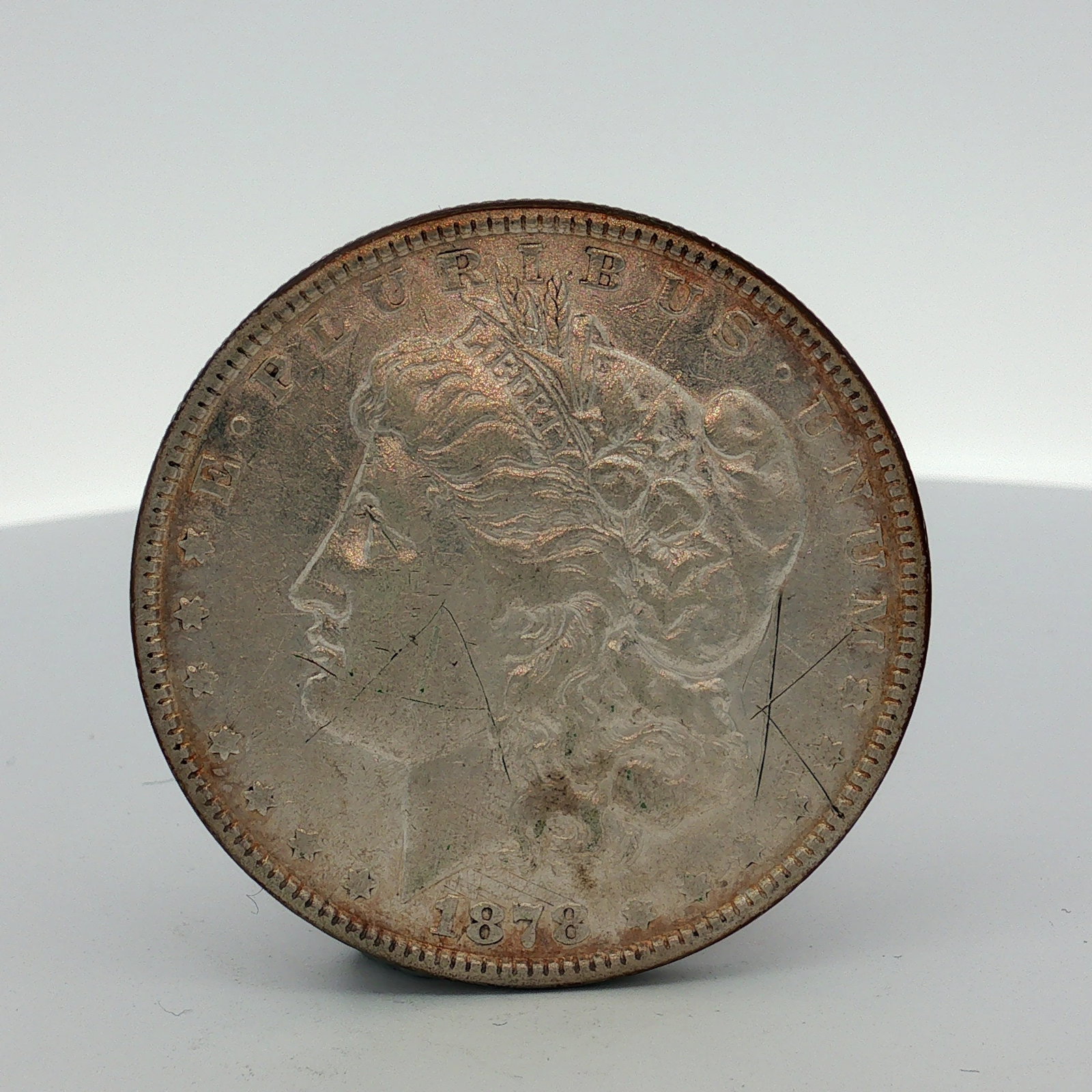 1878 US One Dollar Morgan Silver Dollar-7 Tail Feathers, Circulated: US 1878 Morgan silver dollar was struck at the Philadelphia mint. This struck coin is composed of .900 fine silver. The obverse features the Liberty head design and the reverse displays the heraldic e
