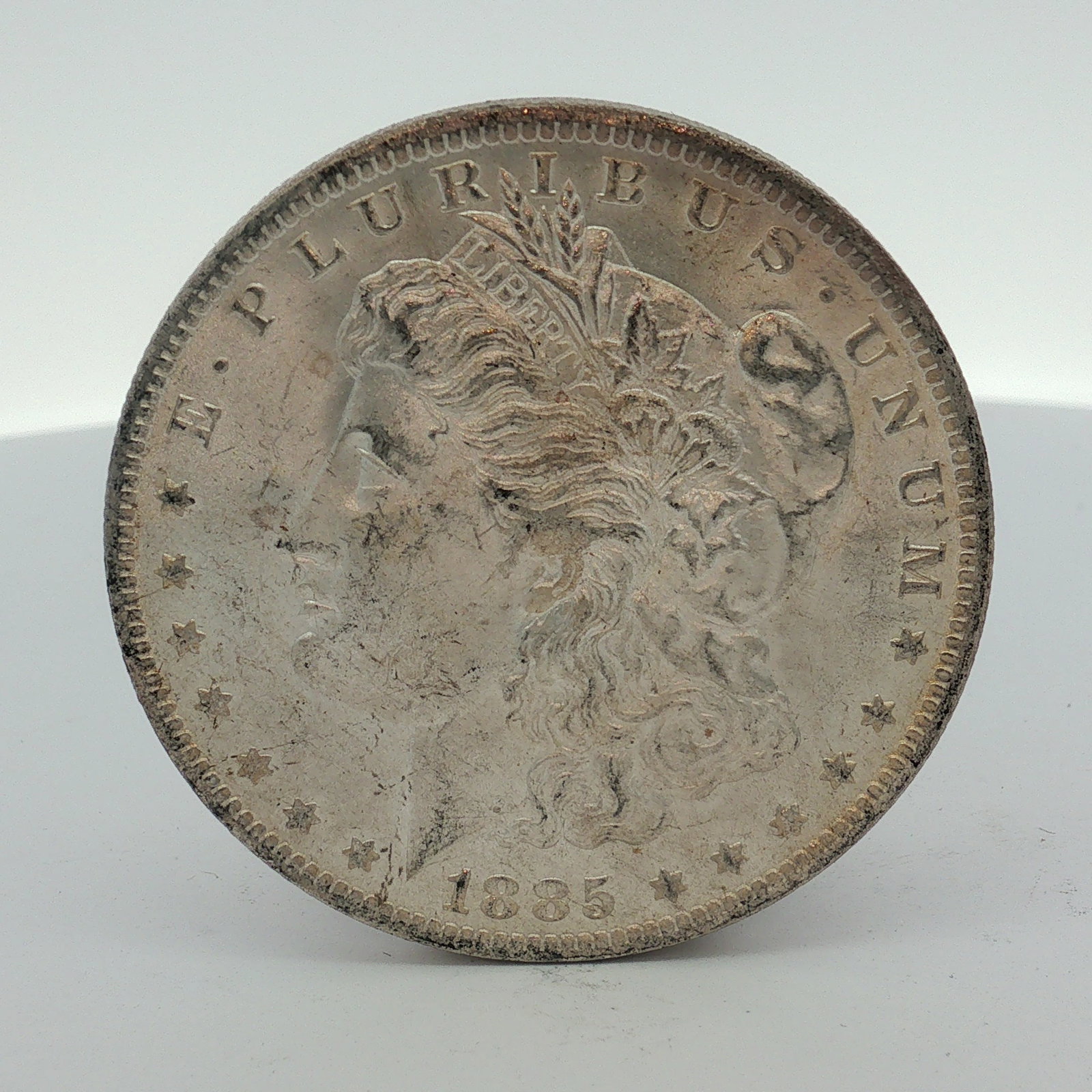 1885-O US Morgan Silver Dollar: This US silver Morgan dollar is dated 1885 and features the O mint mark for the New Orleans mint centered on the reverse below the wreath. The coin is struck in 90 percent silver and 10 percent copper