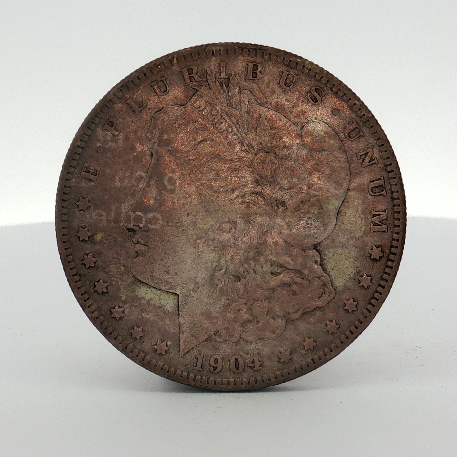 1904-S US One Dollar Morgan Silver Dollar, Circulated: This US 1904-S Morgan silver dollar was struck at the San Francisco mint. The coin features the Morgan dollar obverse and the heraldic eagle reverse. The S mint mark is located on the reverse above th