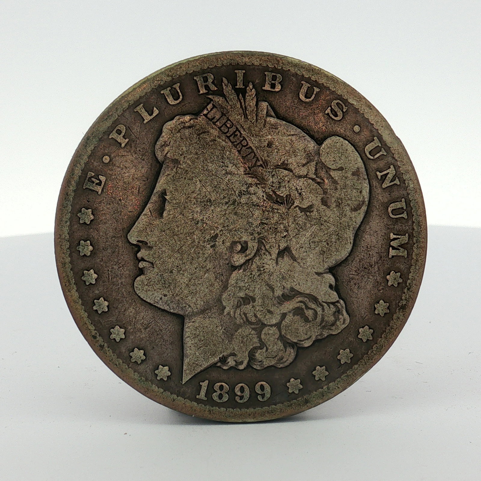 1899-S US One Dollar Morgan Silver Dollar, Circulated: This US 1899-S Morgan dollar is struck in .900 fine silver. The obverse features the Morgan design with the date 1899. The reverse includes the S mint mark for the San Francisco Mint. The coin feature