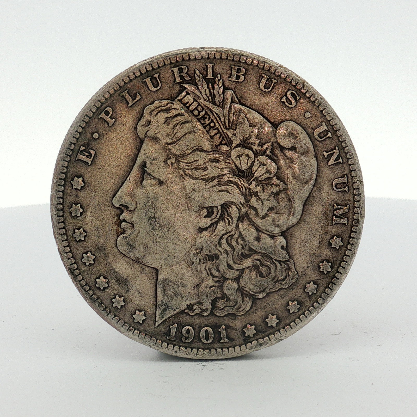 1901-S US One Dollar Morgan Silver Dollar, Circulated: This US silver coin is a Morgan dollar produced at the San Francisco Mint. The piece features the Morgan Liberty obverse and the heraldic eagle reverse. It is struck in silver with a reeded edge. The 
