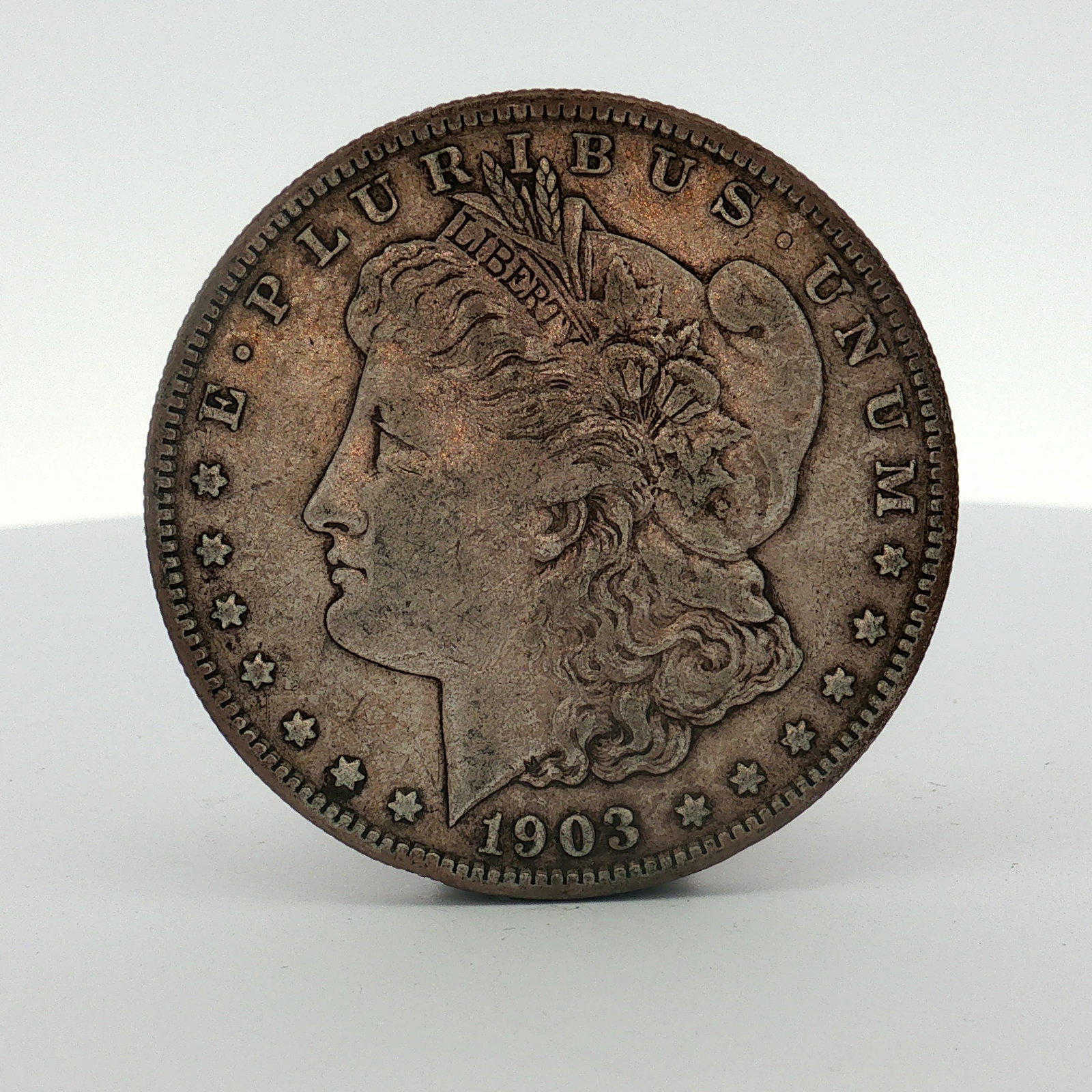 1903-S US One Dollar Morgan Silver Dollar, Circulated: This US silver Morgan dollar was struck at the San Francisco Mint in 1903. The coin is composed of 90 percent silver and 10 percent copper with a fineness of .900. The obverse displays the Liberty hea