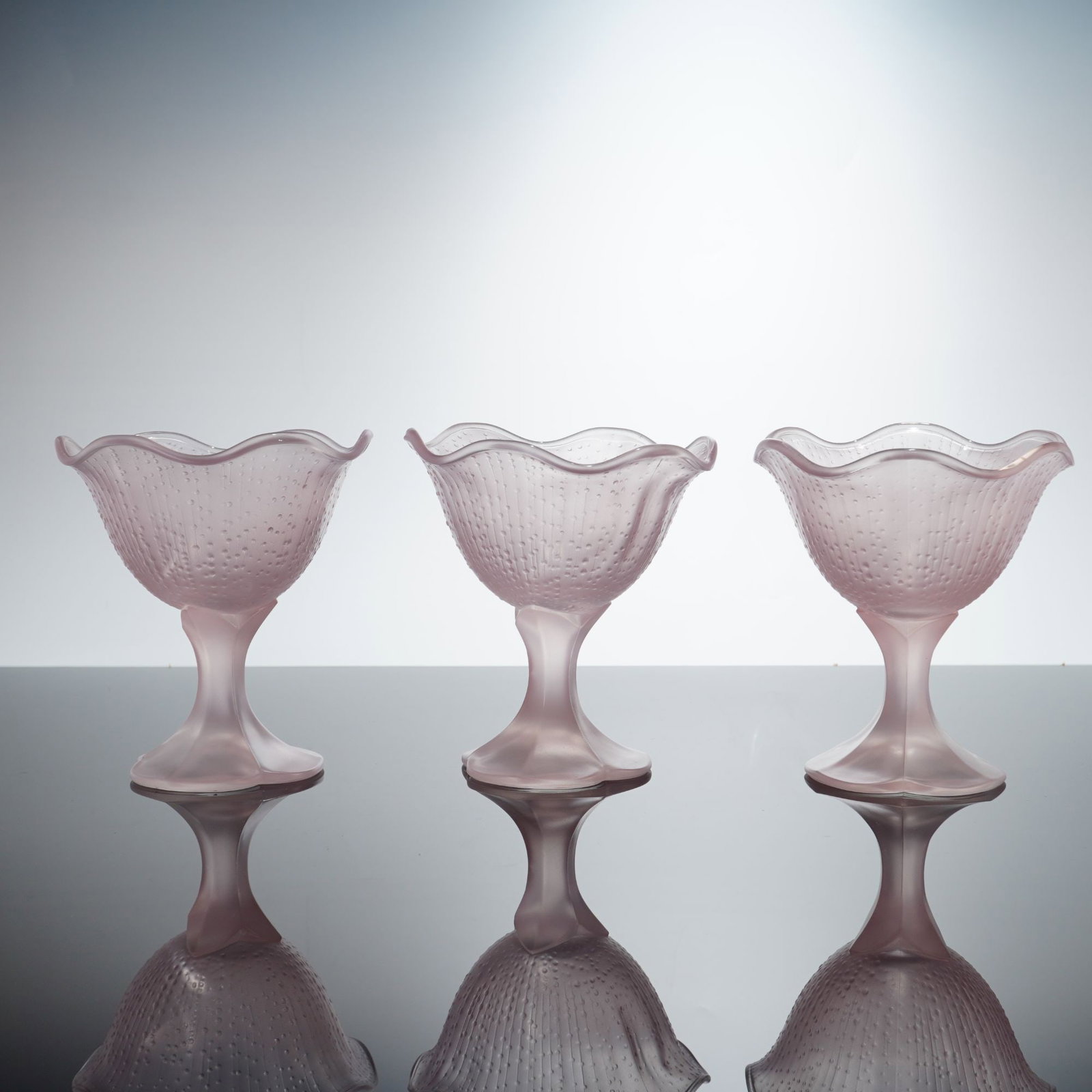 3pc French Frosted Pink Glass Tulip Petal Base Dessert Coupes: A trio of dessert coupes manufactured in France, as evidenced by the embossed mark on the base. Each vessel is constructed from heavy frosted satin glass in a soft pink color. The design features a wi