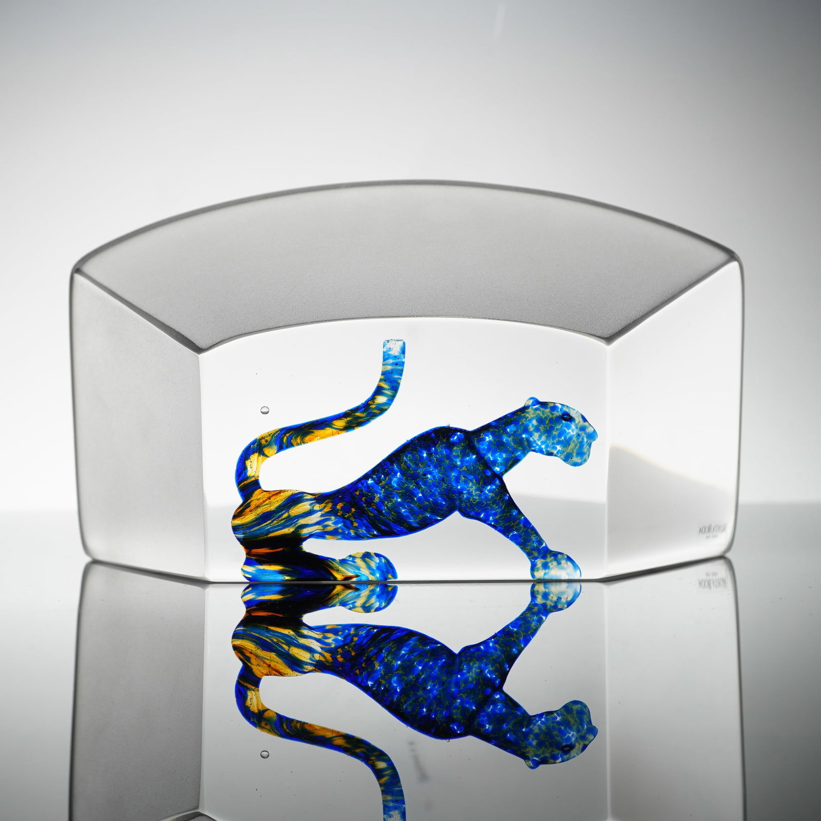 Bertil Vallien for Kosta Boda Viewpoints Art Glass Sculpture, Panther: The piece features a solid, heavy clear glass block with an internal stylized figure of a panther. The animal figure is rendered in cobalt blue glass with mottled yellow and amber swirls suggesting a 