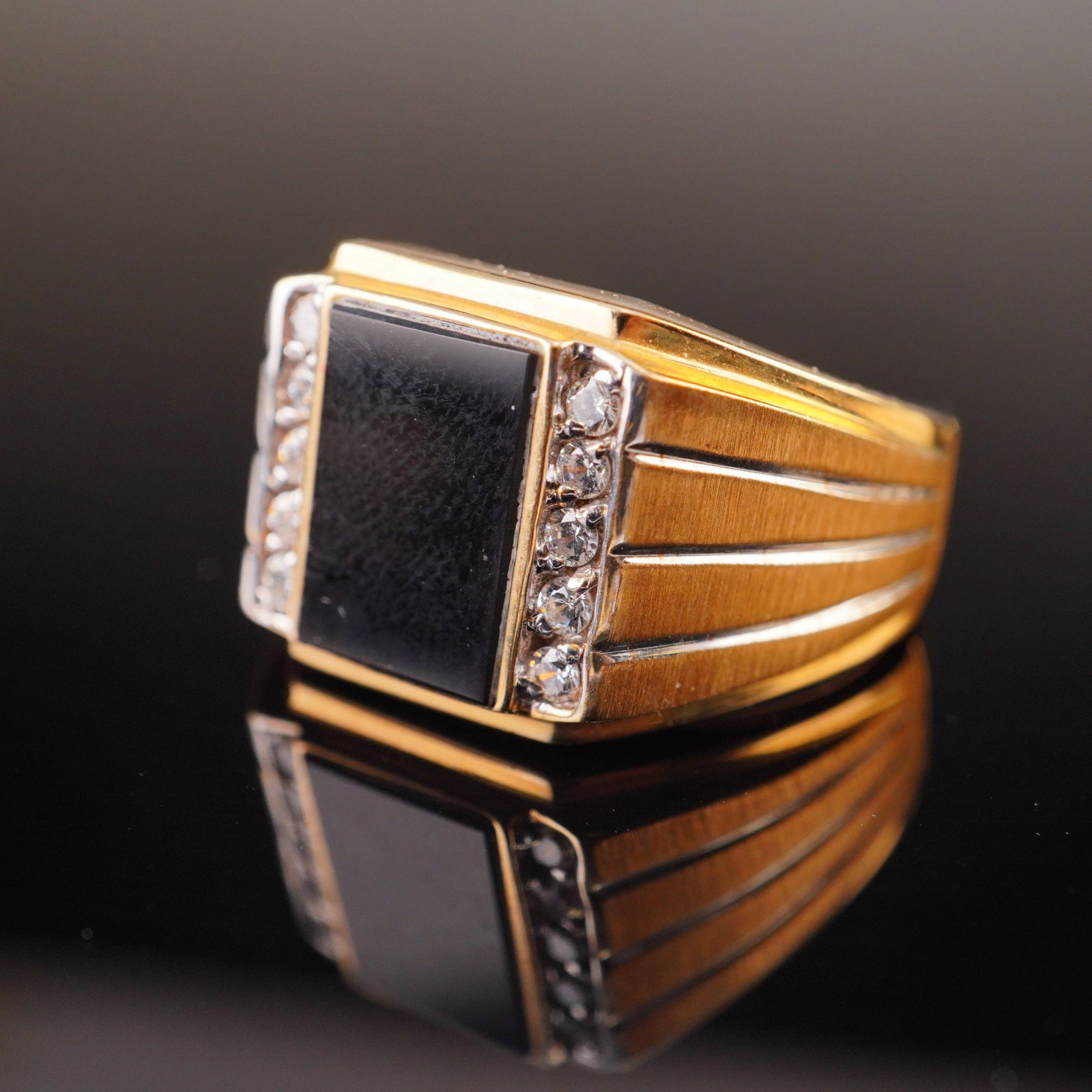 Men's 10K Yellow Gold Black Onyx and Diamond Accent Statement Ring: This men's rectangular-head fashion ring is constructed from 10 karat yellow gold with white gold accents. The focal point is a flush-set rectangular-cut black onyx stone. The center stone is flanked 