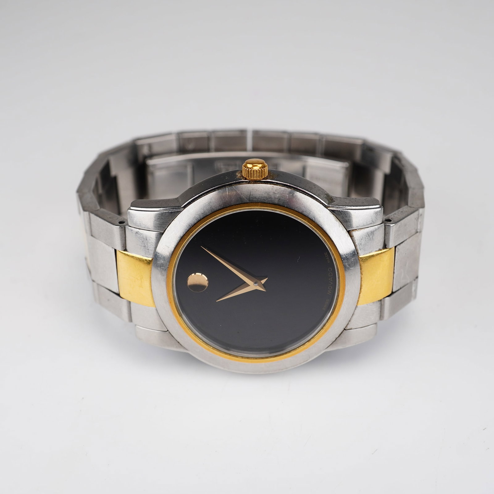 Movado Junior Sport Men's Watch with Case: Movado Junior Sport, reference 81 E4 1893. Quartz movement. Two-tone stainless steel case with gold-toned bezel and crown. Black Museum dial featuring a gold-toned signature dot at 12 o'clock and gold