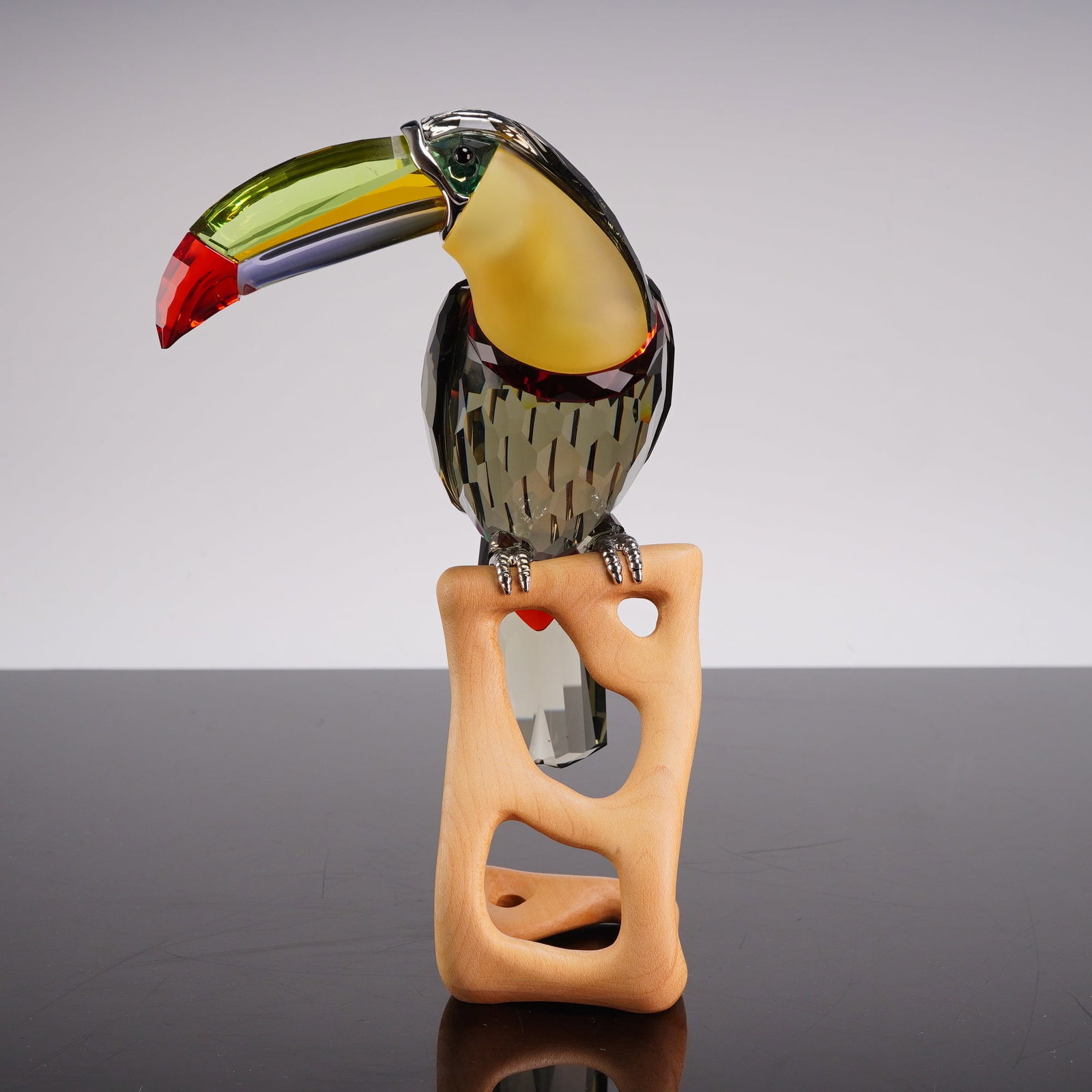 Swarovski Crystal Paradise Bird Black Diamond Toucan Figurine 850600: This Swarovski crystal figurine depicts a toucan from the Paradise Birds collection, model 850600. The bird is constructed from multi-colored faceted and frosted lead crystal. The beak features segmen