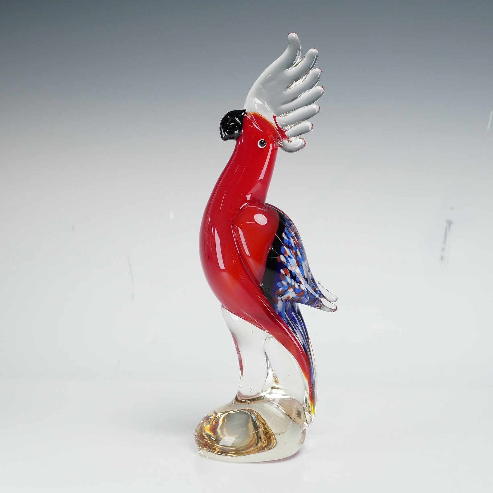 Art Glass Parrot Figurine: Art glass figurine of a parrot or crested bird designed in the mid-century modern style. The piece is crafted from polychrome glass featuring a vibrant translucent red body. The bird is depicted with 