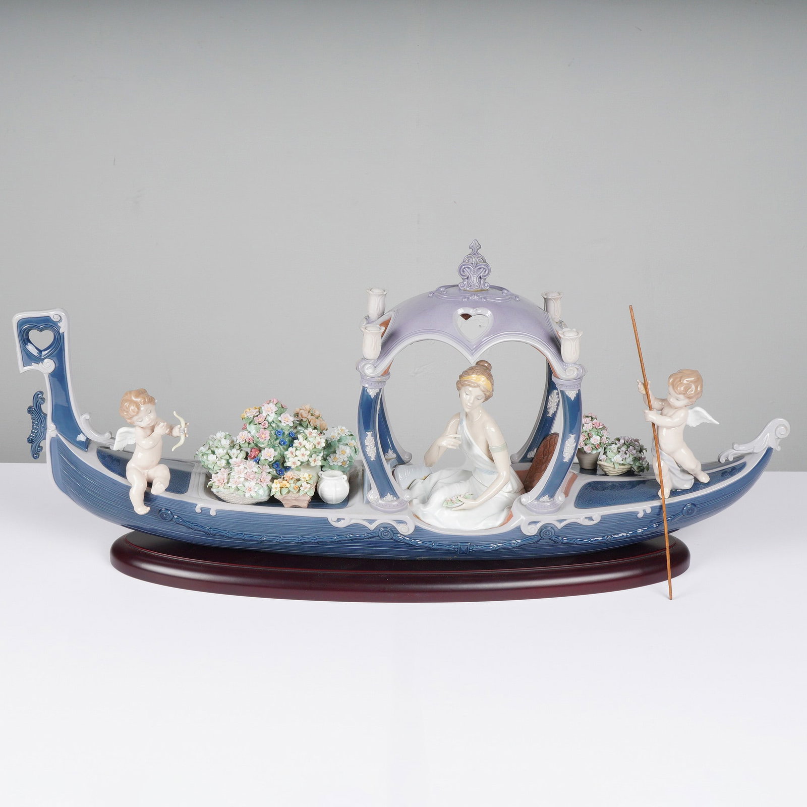 Lladro Limited Edition Gondola of Love Porcelain Sculpture 01001870: A limited edition Lladro Gondola of Love porcelain sculpture, model 01001870, featuring a woman and two cherubs in a blue and white gondola on a wooden base, sculpted by Juan Ignacio Aliena and decora