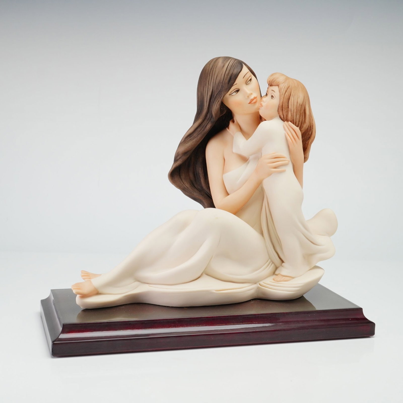 Giuseppe Armani Florence Sculture d'Arte Figurine My Little Girl 2185F: This Giuseppe Armani figurine depicts a seated mother in a flowing white gown embracing a small child. The piece is rendered in a matte-finished material with naturalistic tones for the skin and hair,