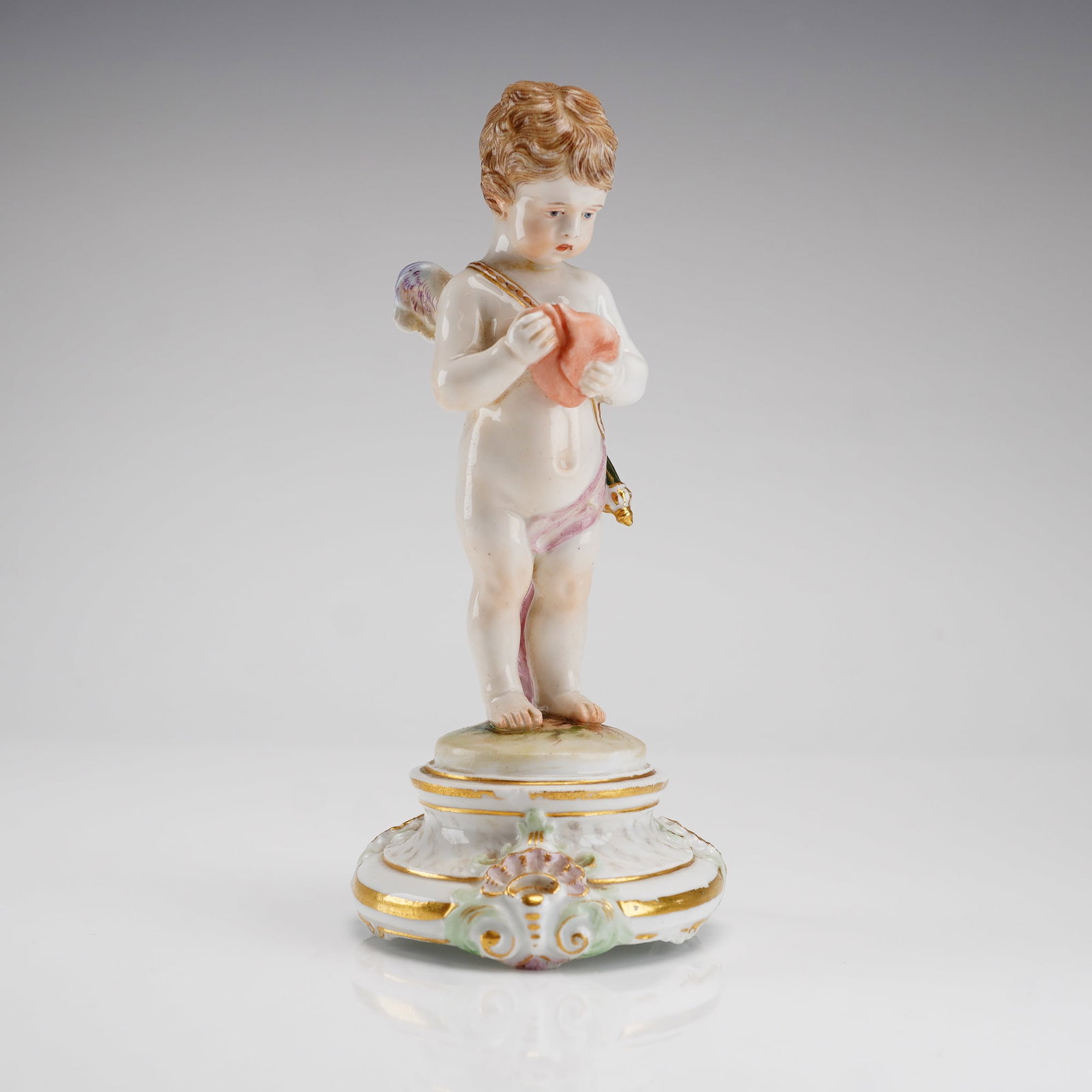 Meissen Porcelain Angel Figurine Cupid with Heart Model M 102: This Meissen porcelain angel figurine depicts a winged Cupid based on an 18th-century model by Michel Victor Acier. Identified as model M 102 and titled Un me suffit (One is enough for me), the standi